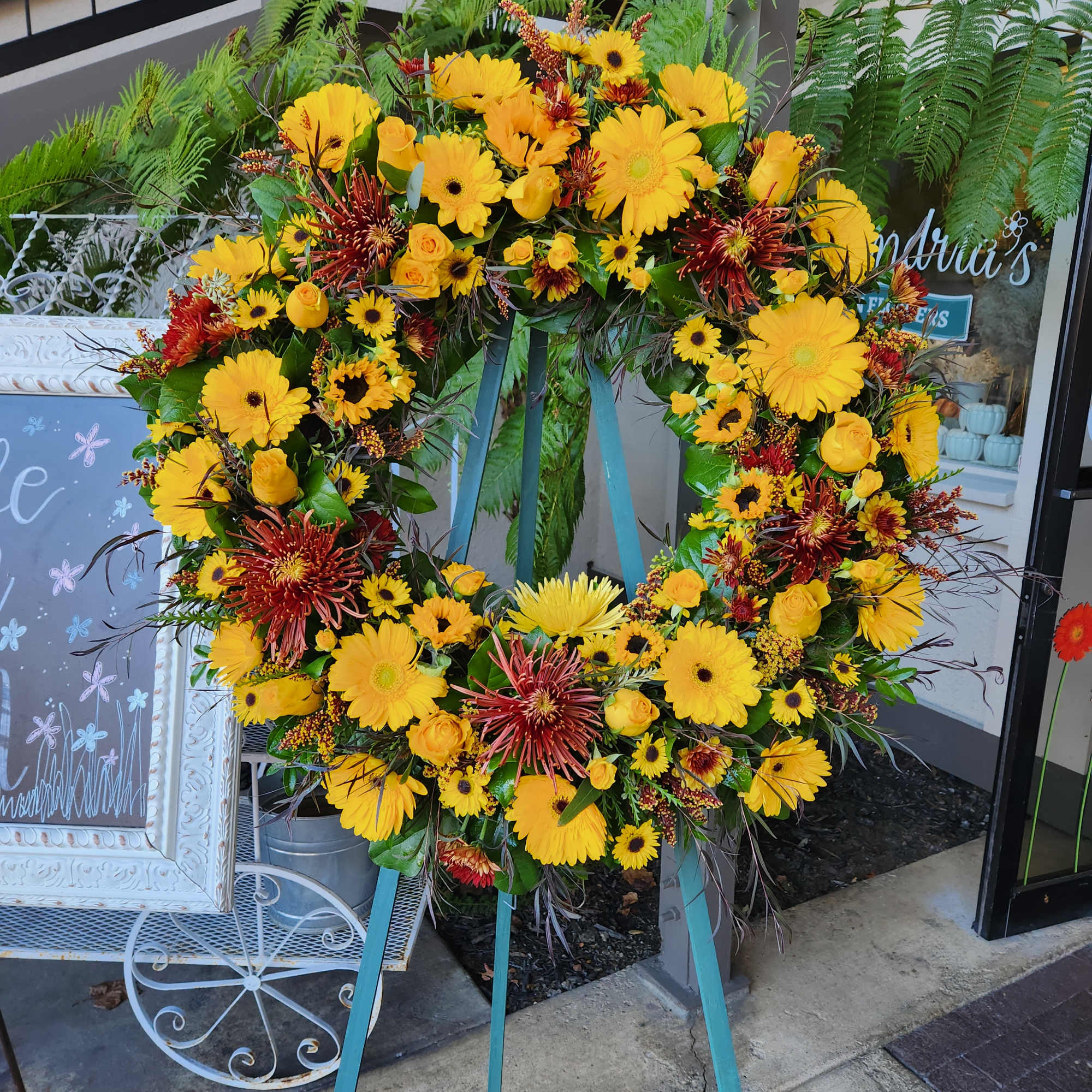 Large yellow and red floral wreath on a stand