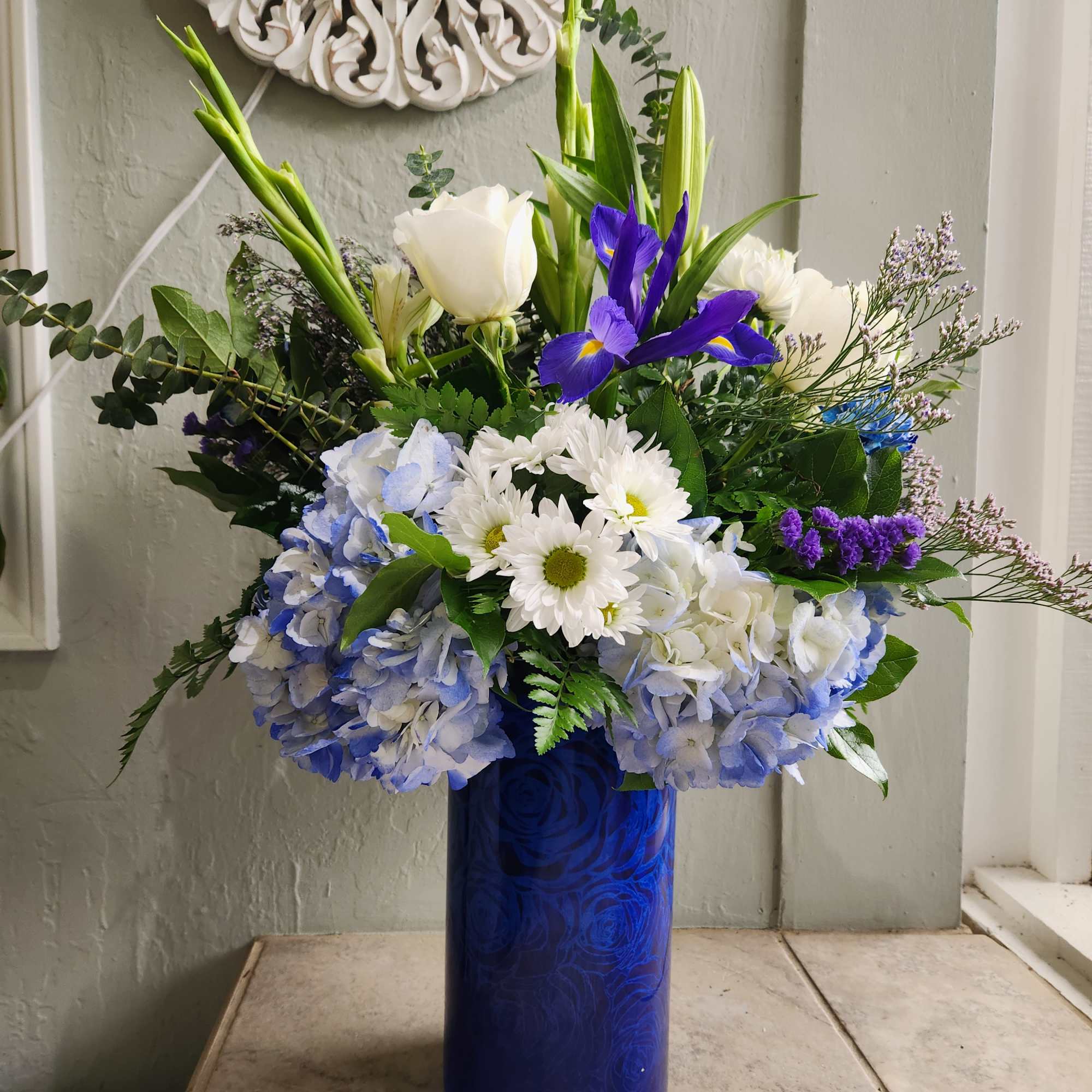 Blue and white floral arrangement in a tall cobalt vase