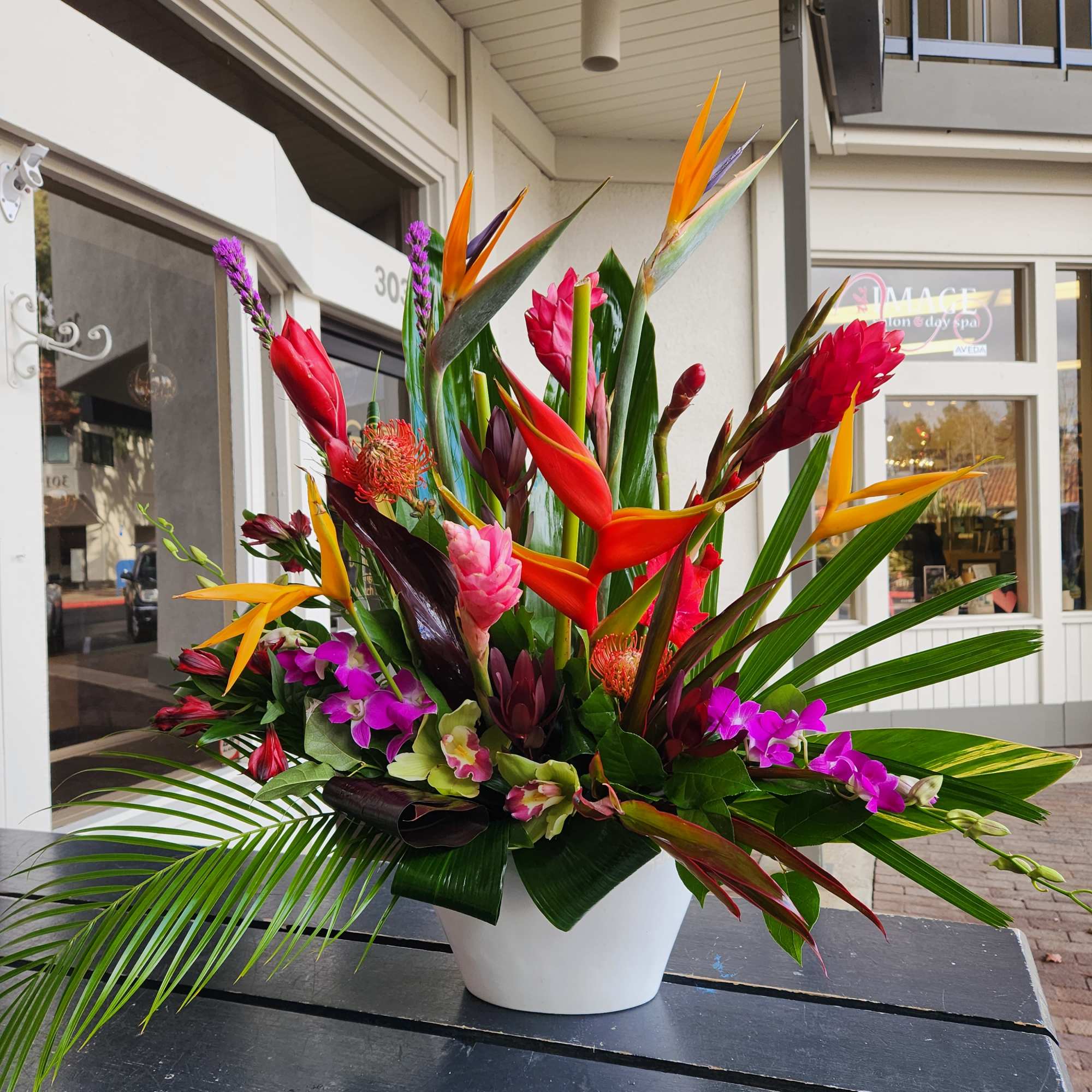 Tropical flower arrangement in a white vase with orange and purple blooms