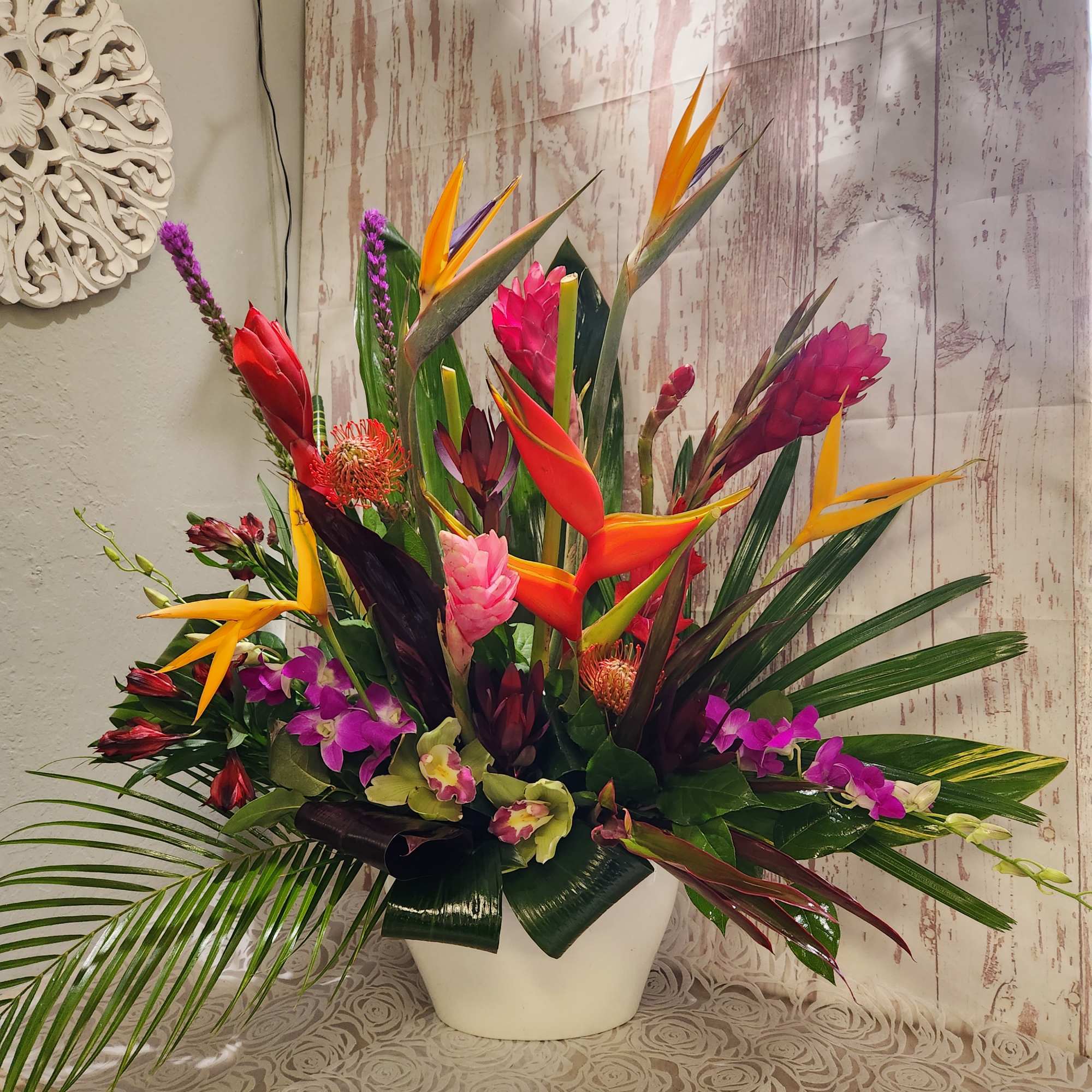 Tropical flower arrangement in a white vase with orchids and bird-of-paradise