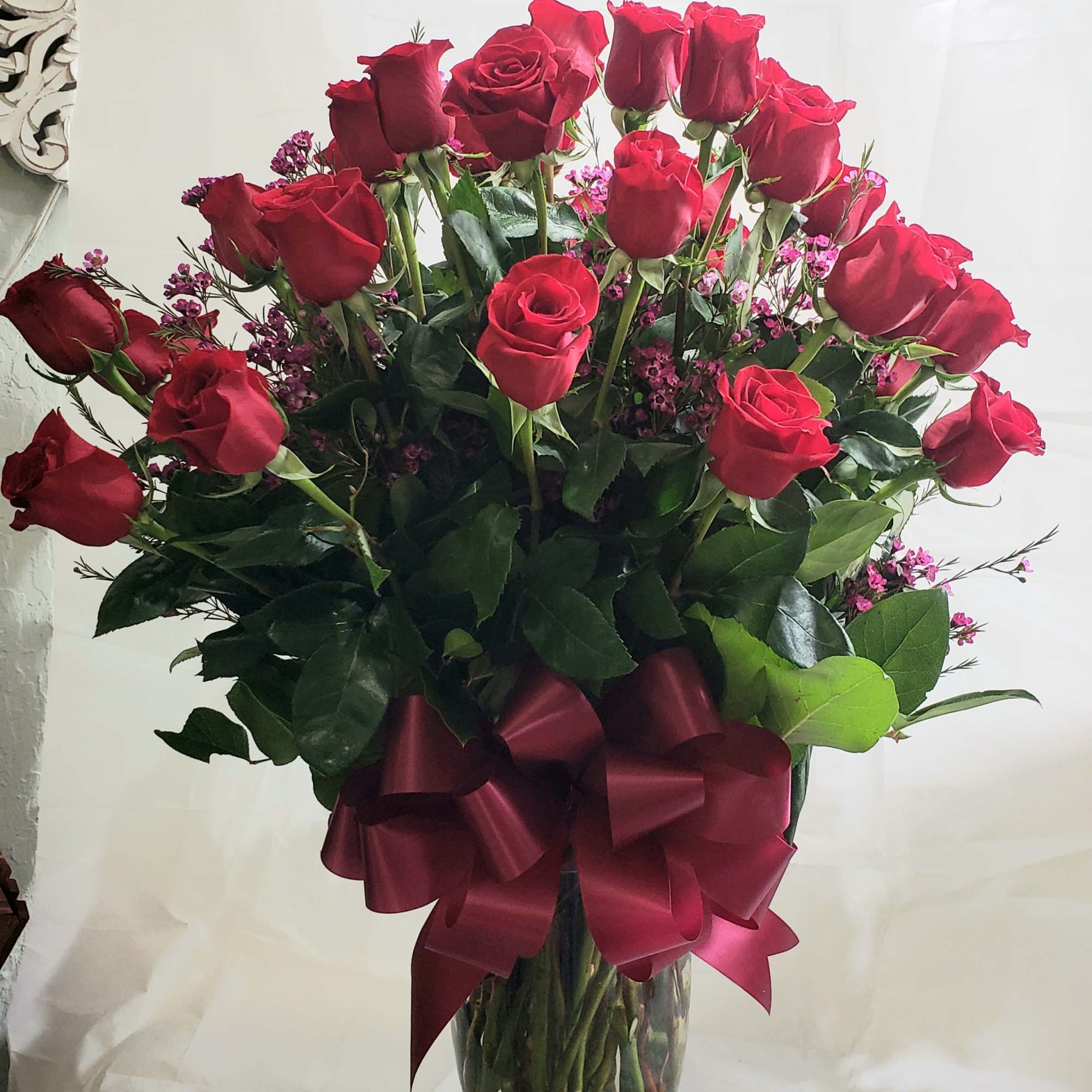 Bouquet of red roses in a clear glass vase with a burgundy ribbon