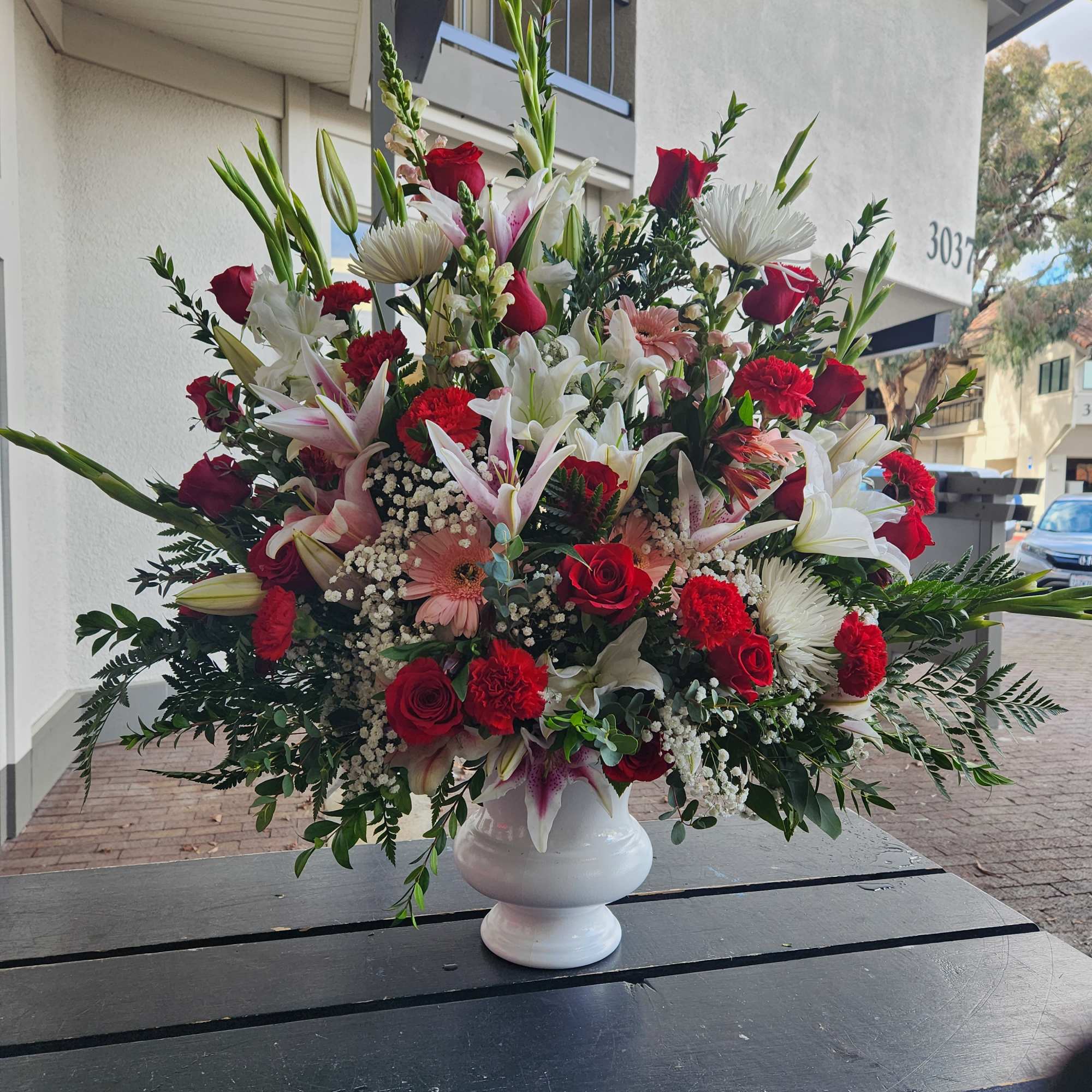 Large mixed bouquet in a white urn vase with red, white, and pink flowers