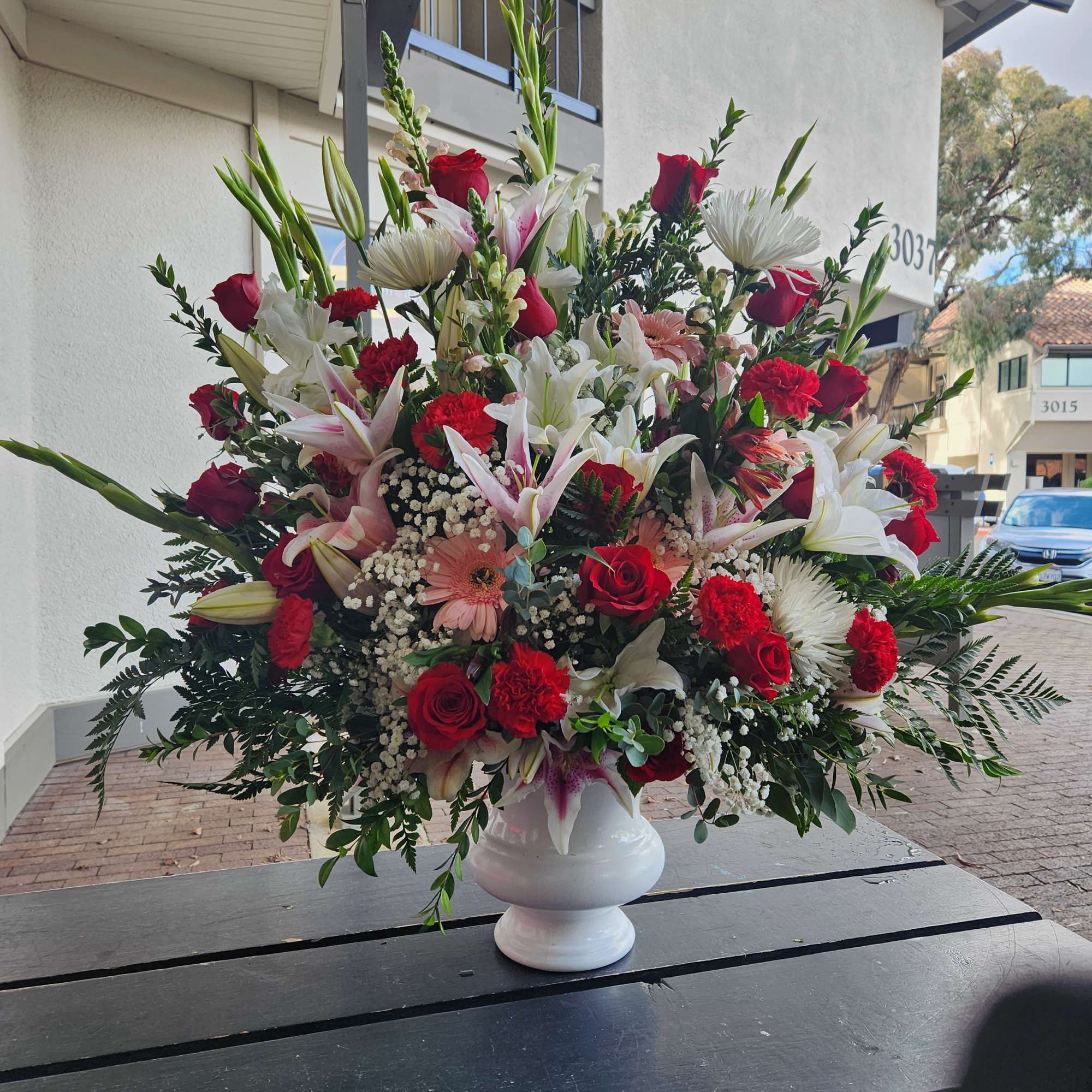 Large red, white, and pink floral arrangement in a white vase
