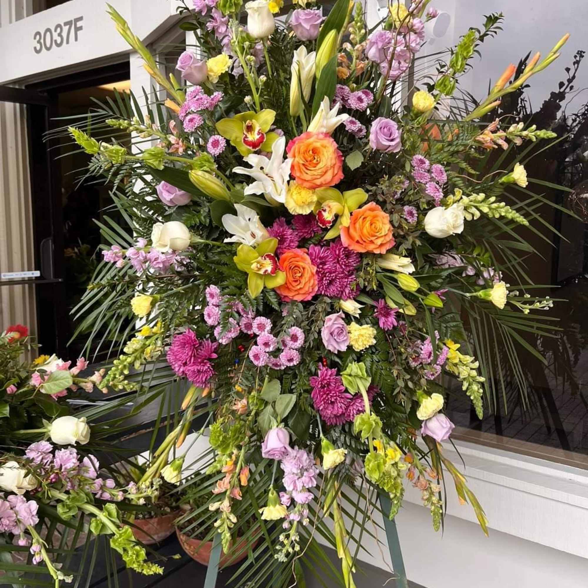 Large standing floral spray with roses, lilies, and orchids in pink, white, and orange