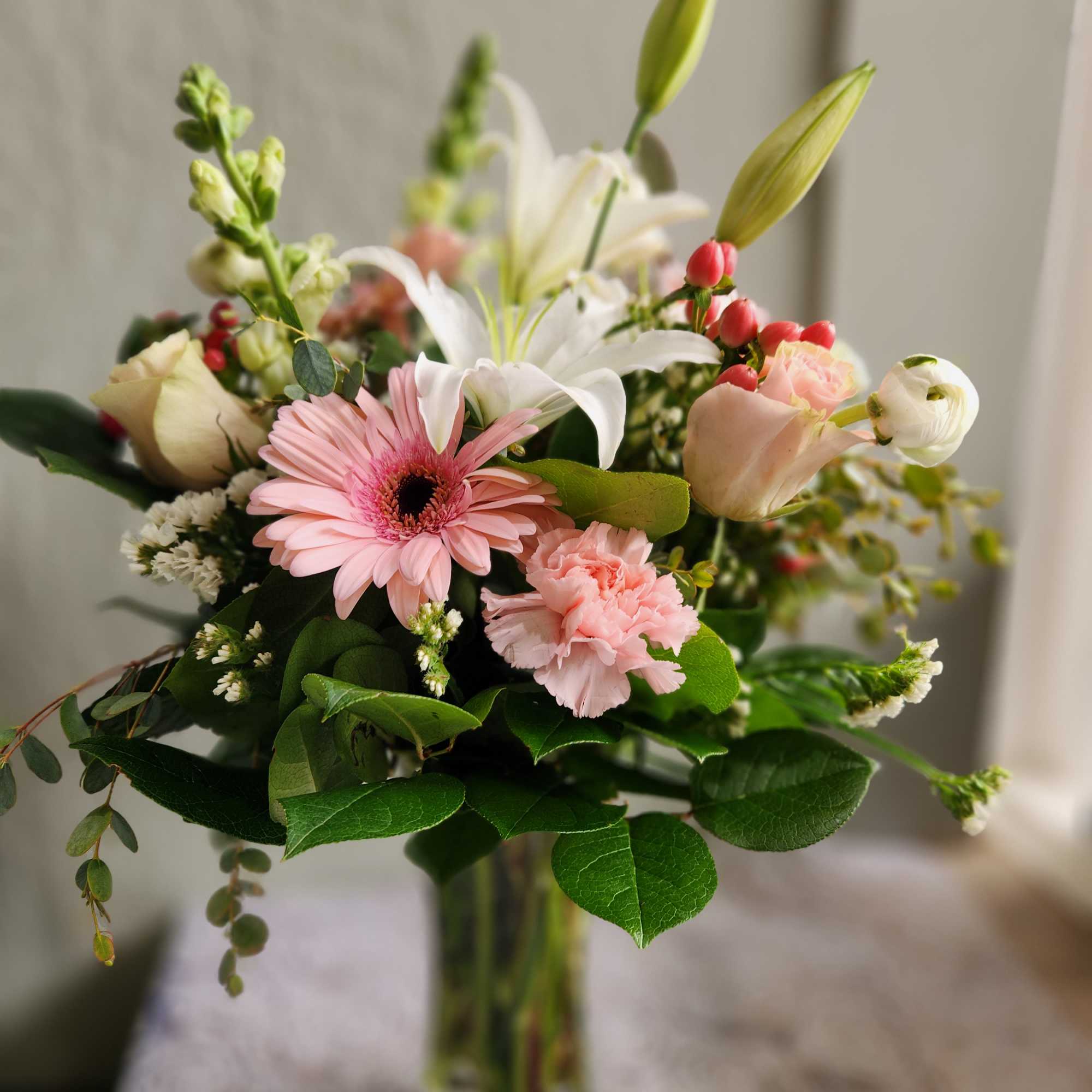 Mixed bouquet with pink gerbera, white lilies, and pale roses in a glass vase