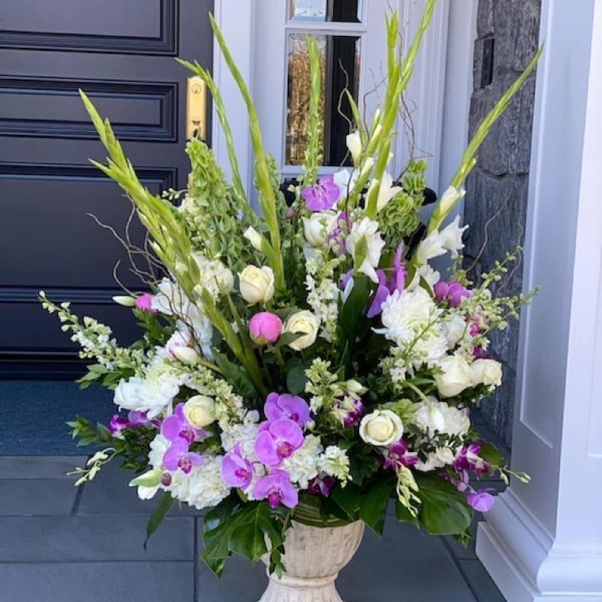 Tall floral arrangement with white and purple blooms in a pedestal urn