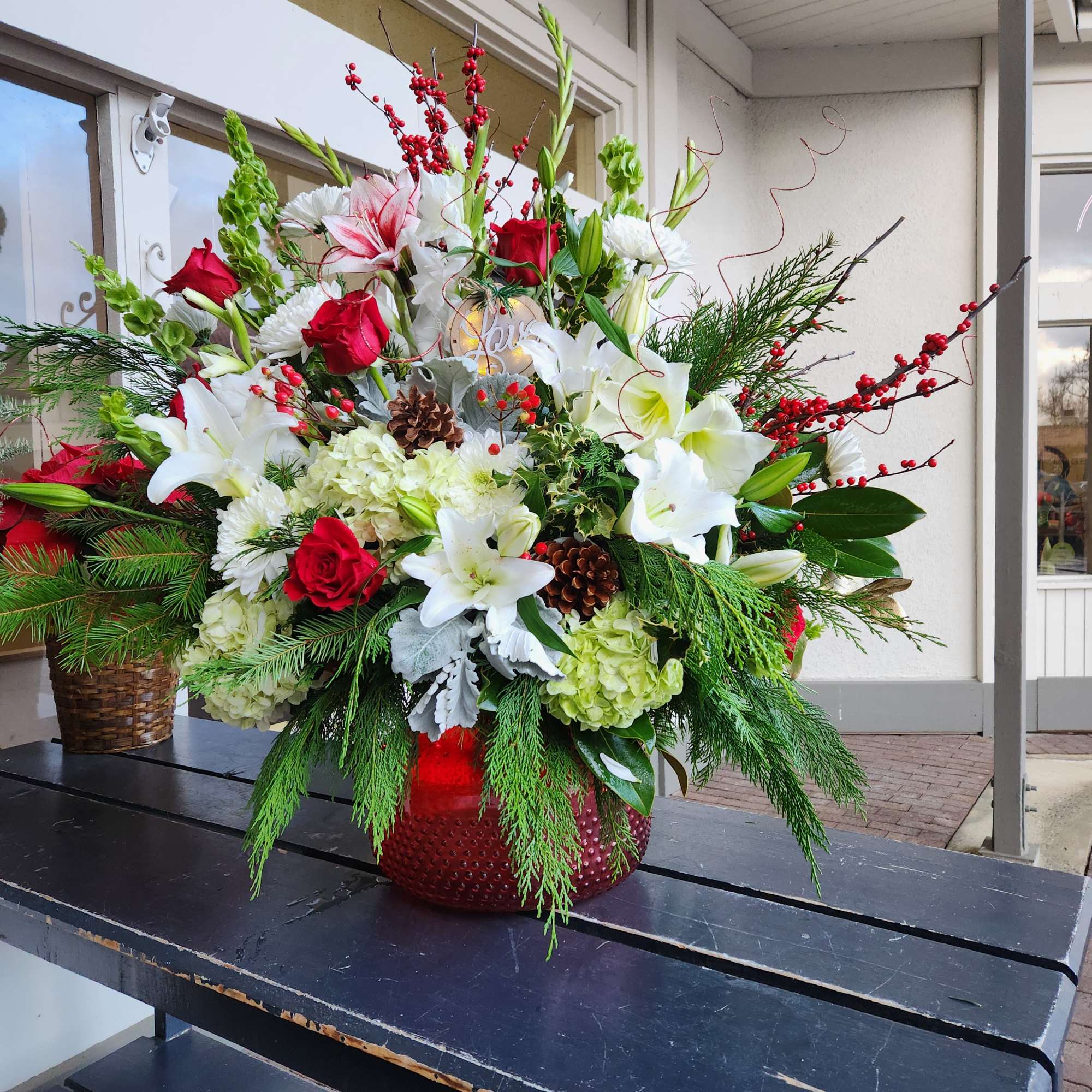 Large holiday arrangement with red and white flowers in a red vase