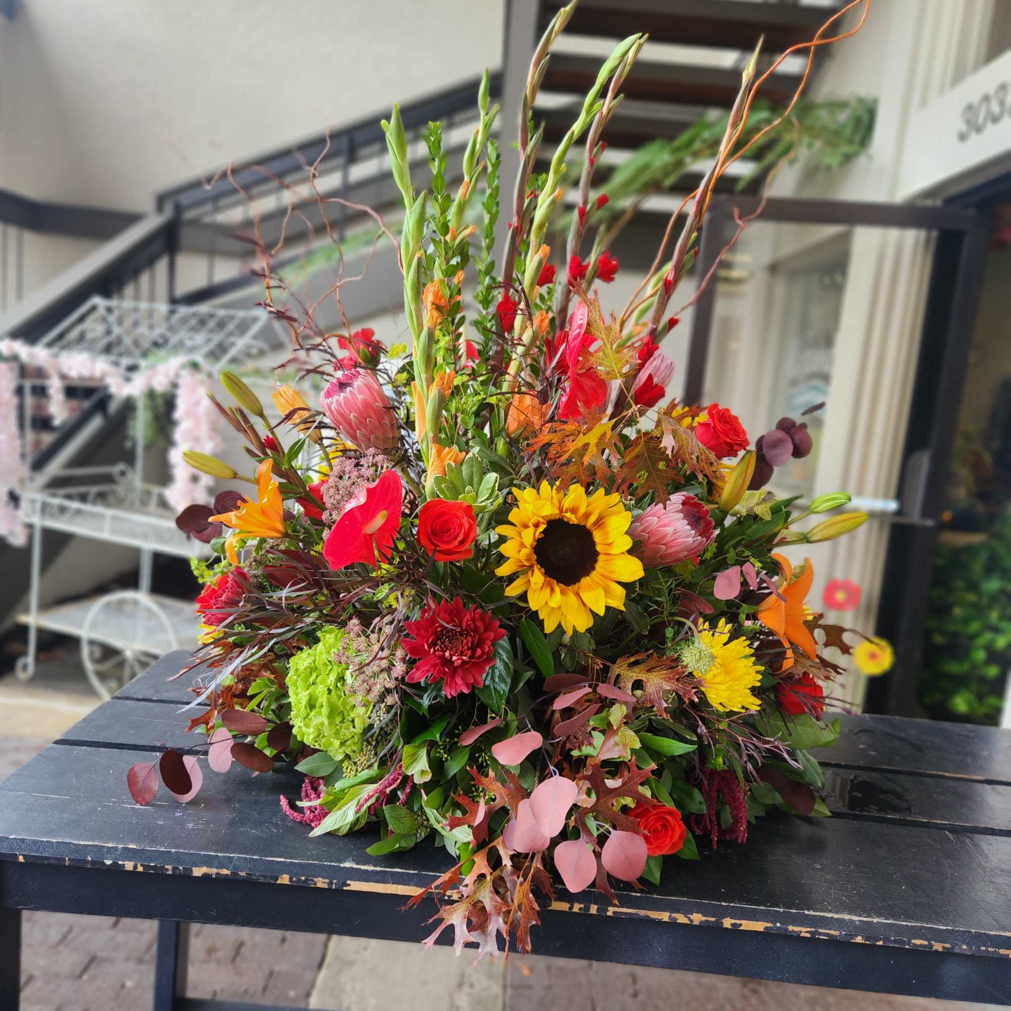Large mixed bouquet with sunflowers, roses, and lilies in bright autumn colors