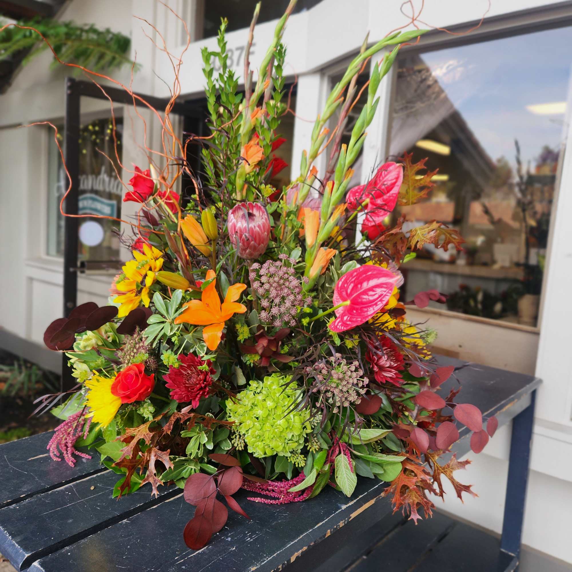 Bright mixed floral arrangement with lilies, roses, and autumn leaves