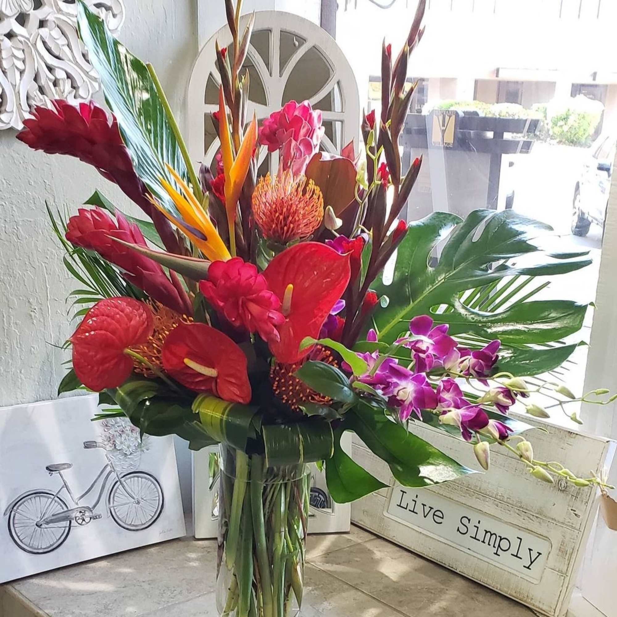 Tropical bouquet in a clear glass vase with red and purple flowers