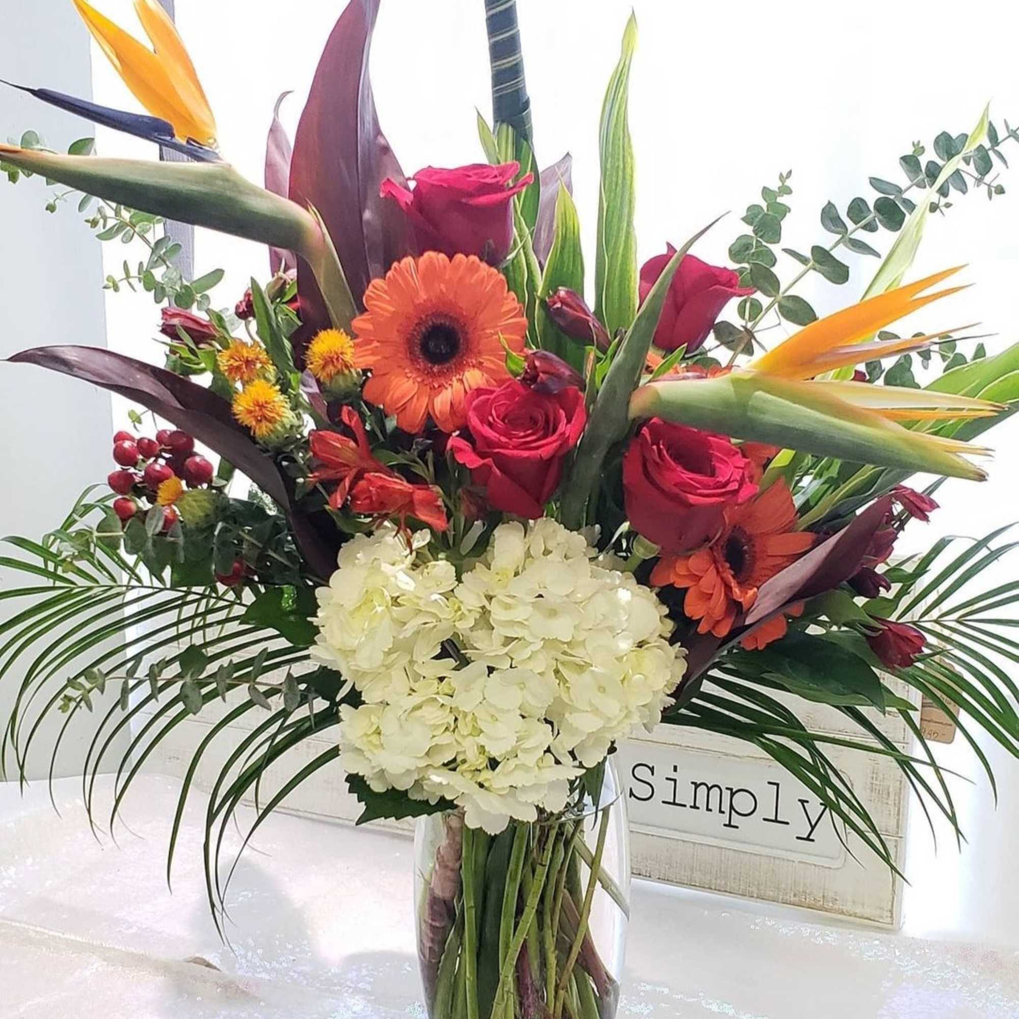 Tall mixed bouquet with red roses, orange gerberas, and white hydrangea in a glass vase