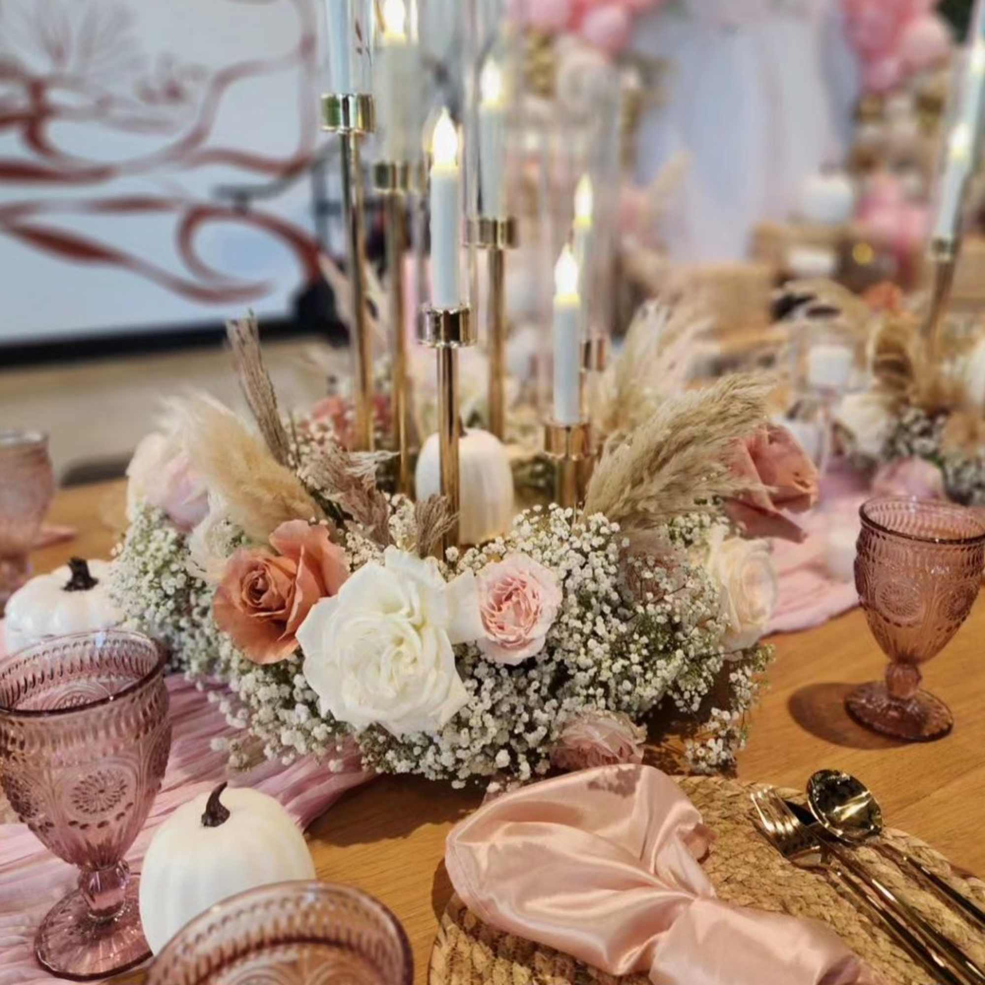 Low floral centerpiece with roses, baby's breath, and candles on a table
