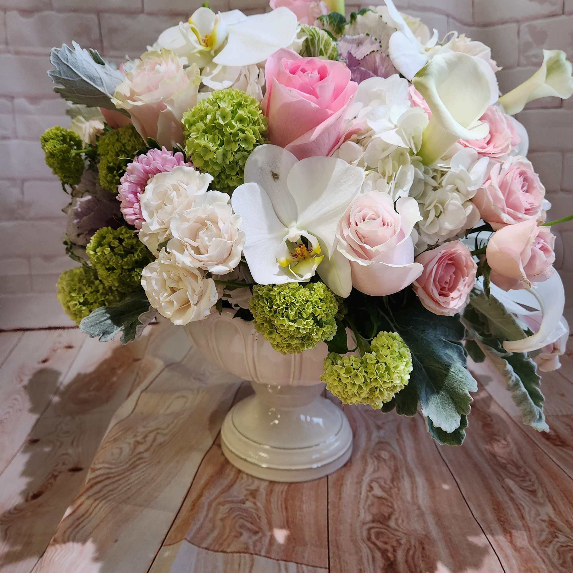 Pink and white floral arrangement in a white pedestal vase