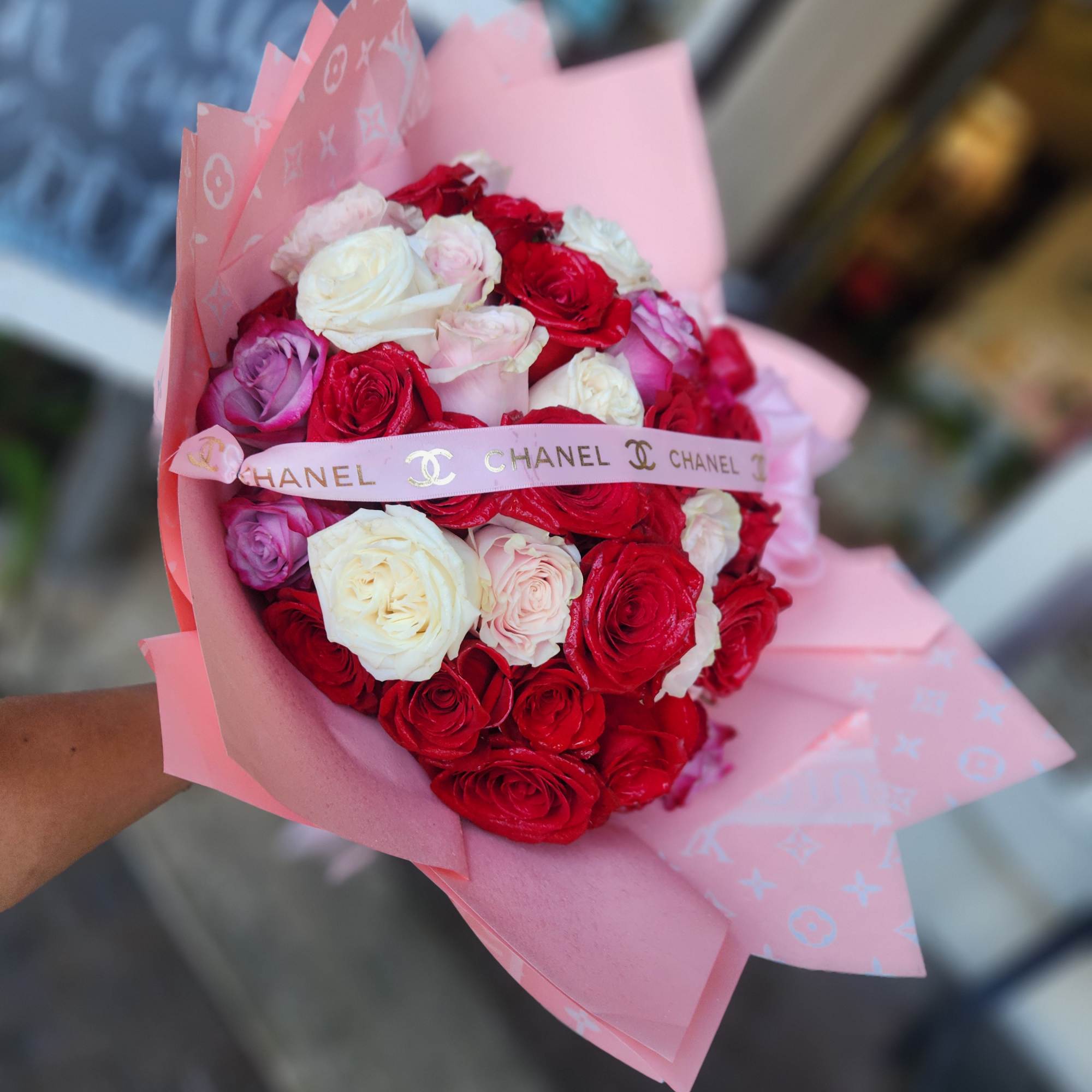Bouquet of red, white, and pink roses wrapped in pink paper