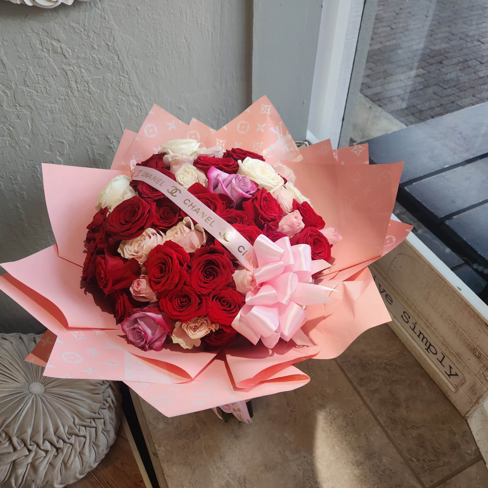Bouquet of red, pink, and white roses wrapped in pink paper with a ribbon