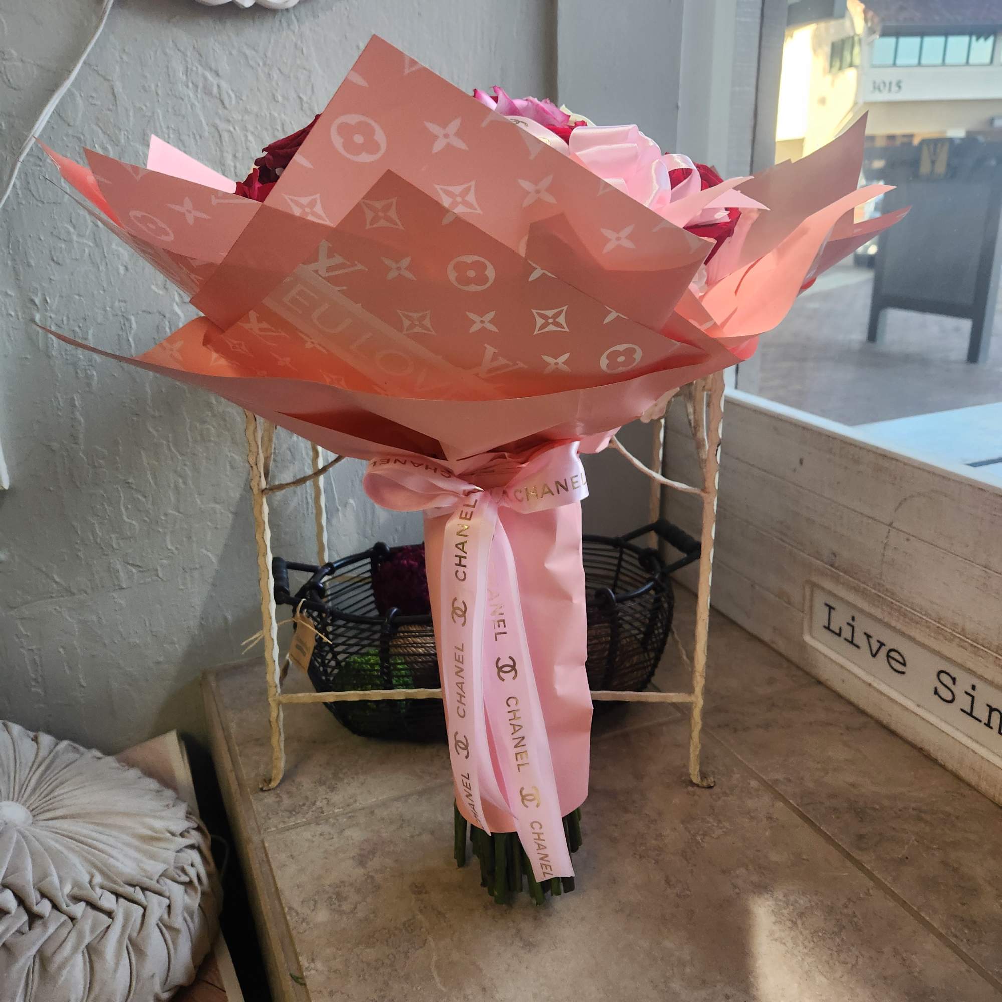 Pink and red bouquet wrapped in patterned paper with a ribbon