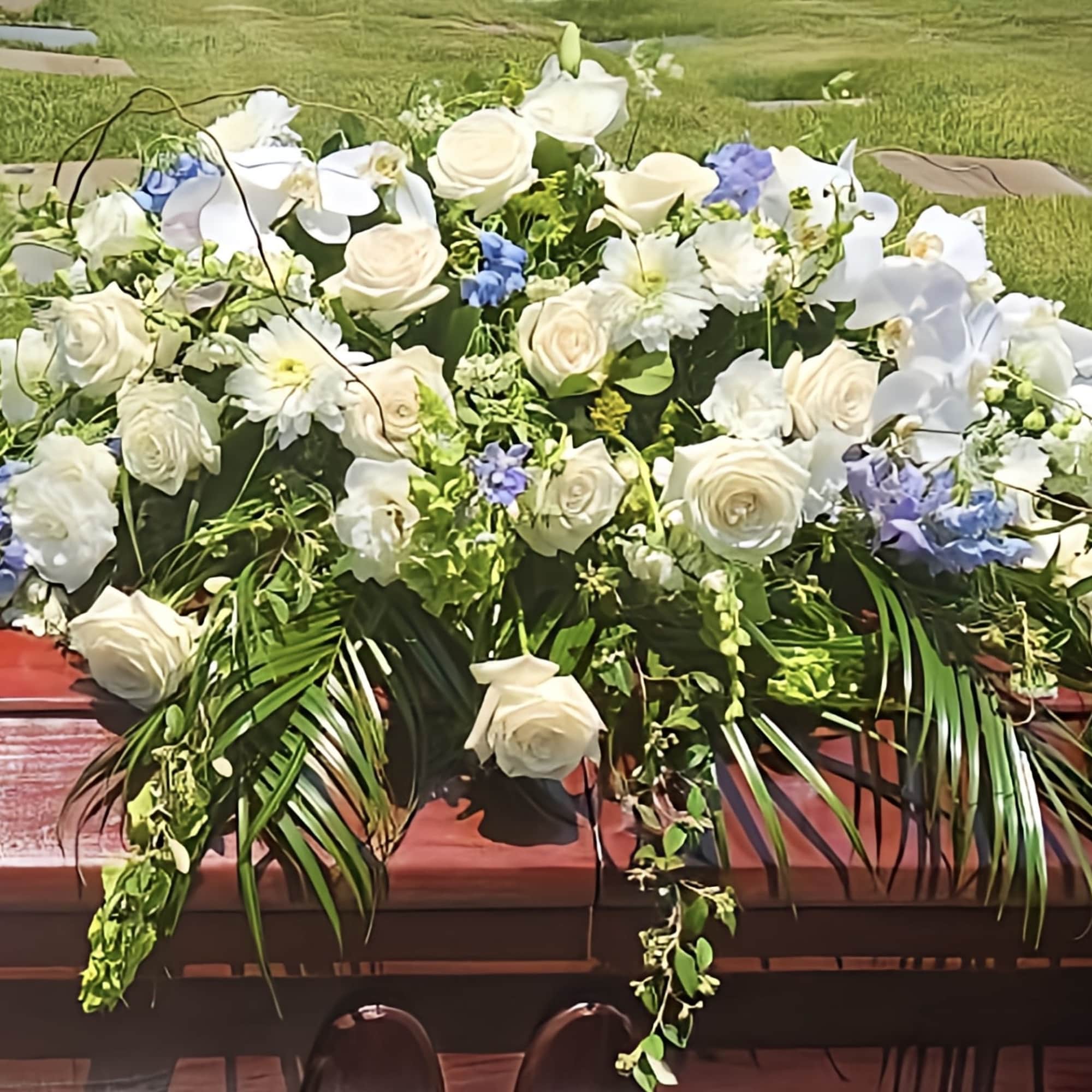 Large white floral casket spray with blue accents