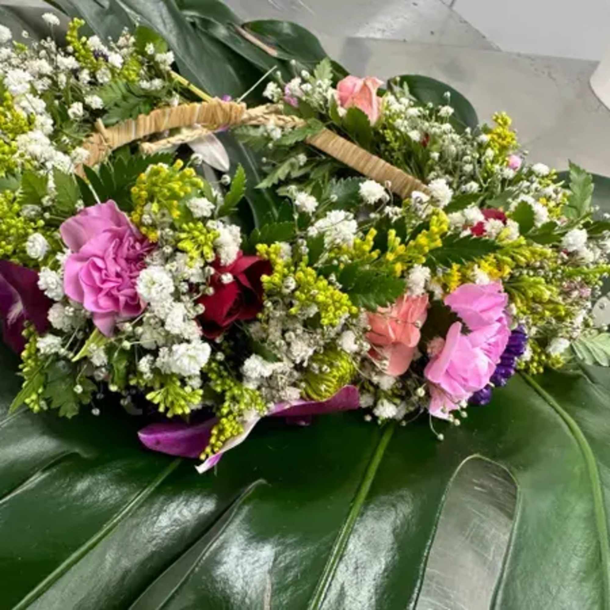 Floral wreath with pink and purple blooms on a woven handle