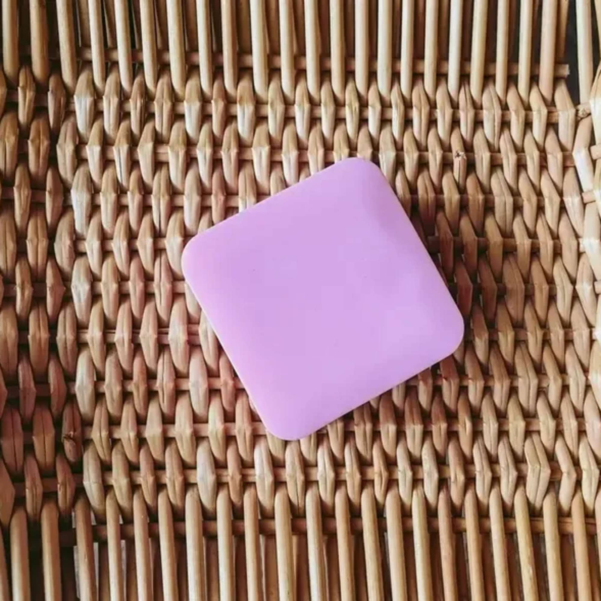 A lavender square soap bar on a woven mat