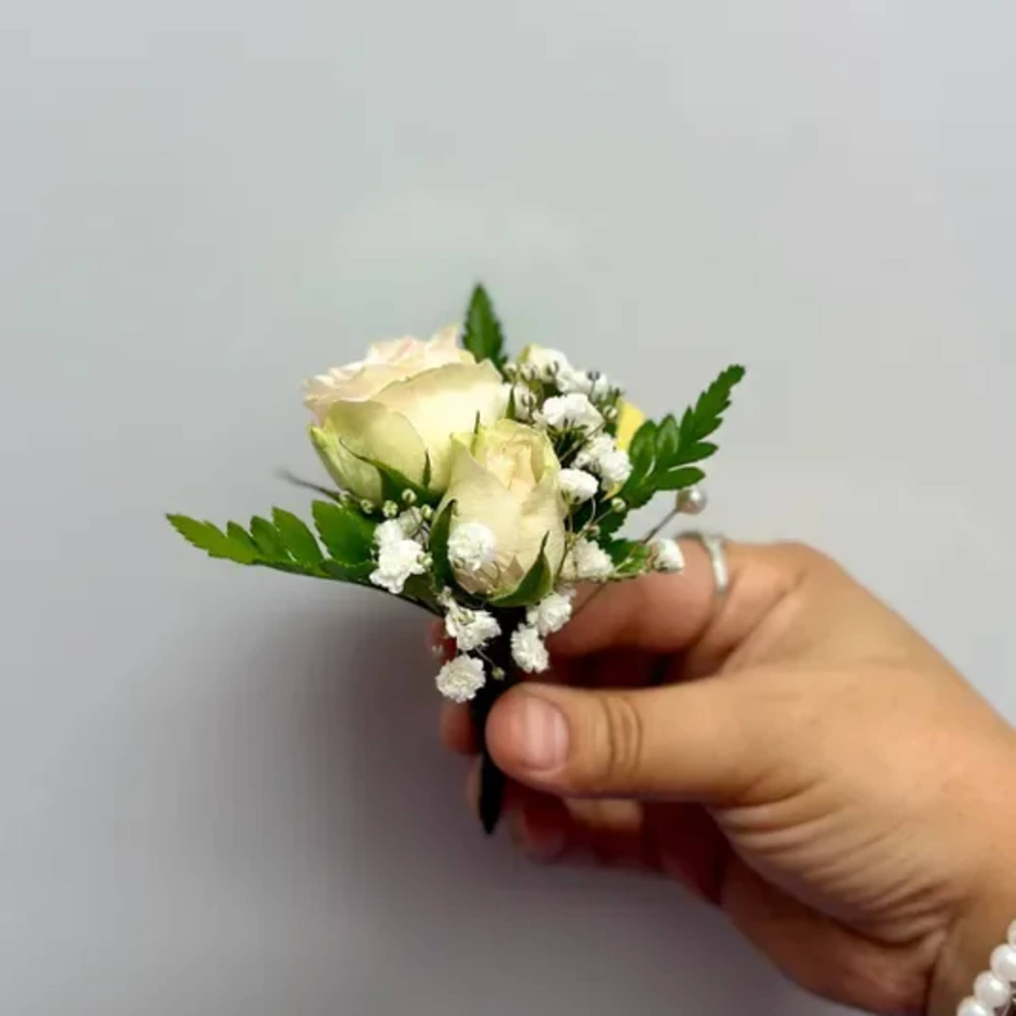 Small white rose boutonniere with baby's breath and greenery