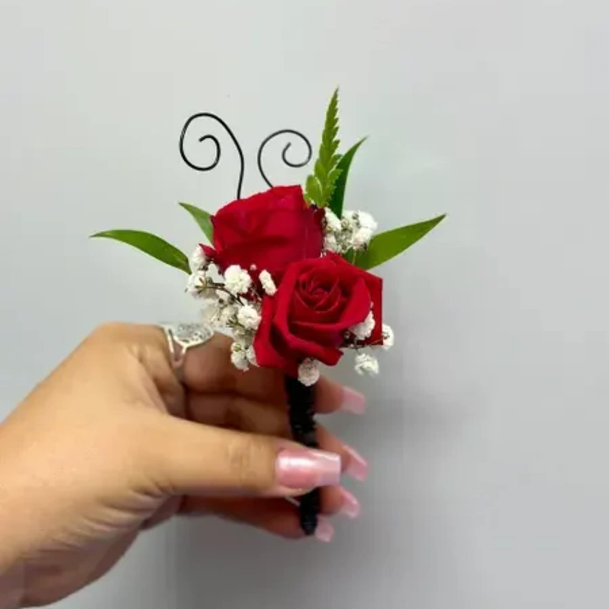 Red rose boutonniere with baby's breath and green leaves
