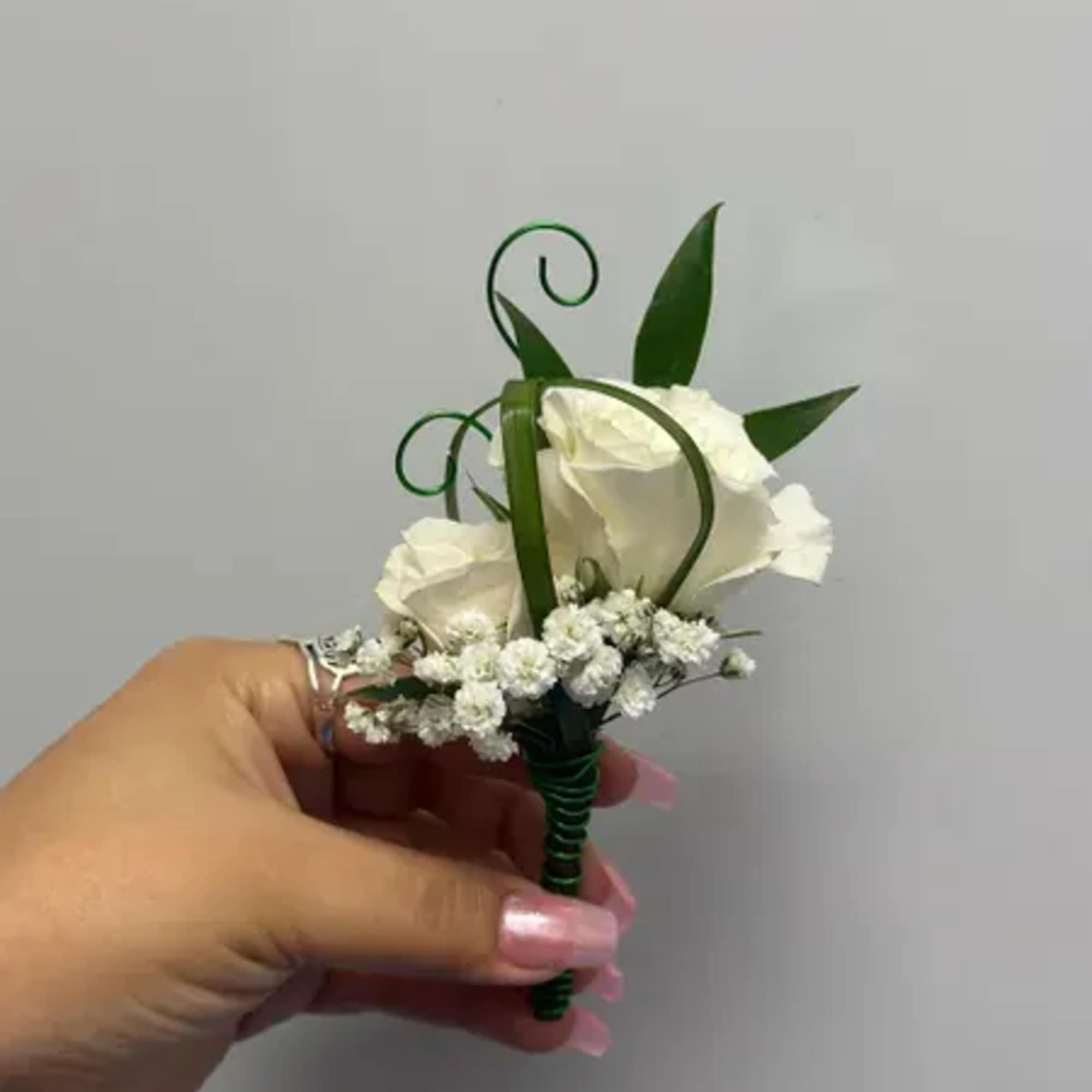 Small white rose boutonniere with baby's breath and green ribbon loops