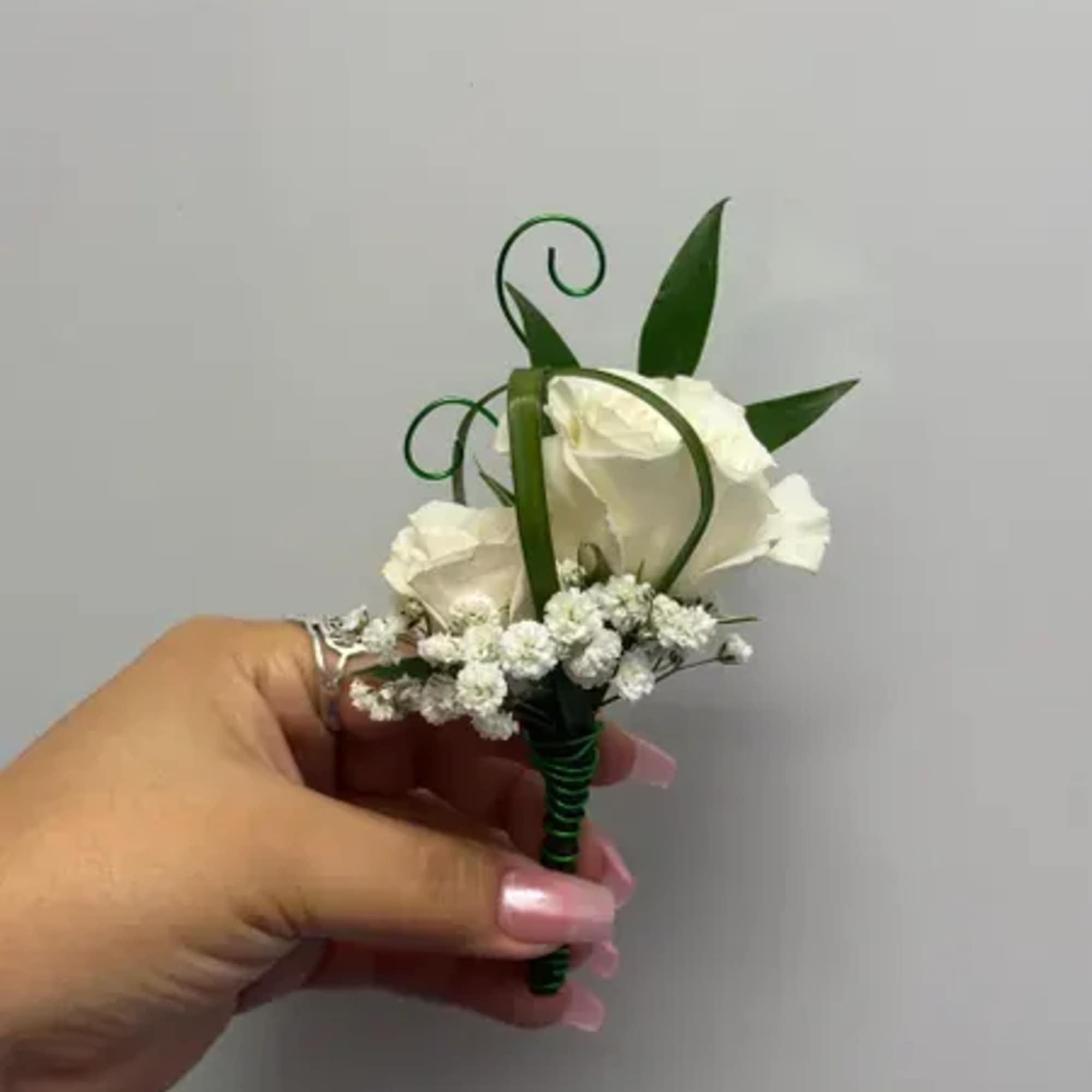 White rose boutonniere with baby's breath and green ribbon curls