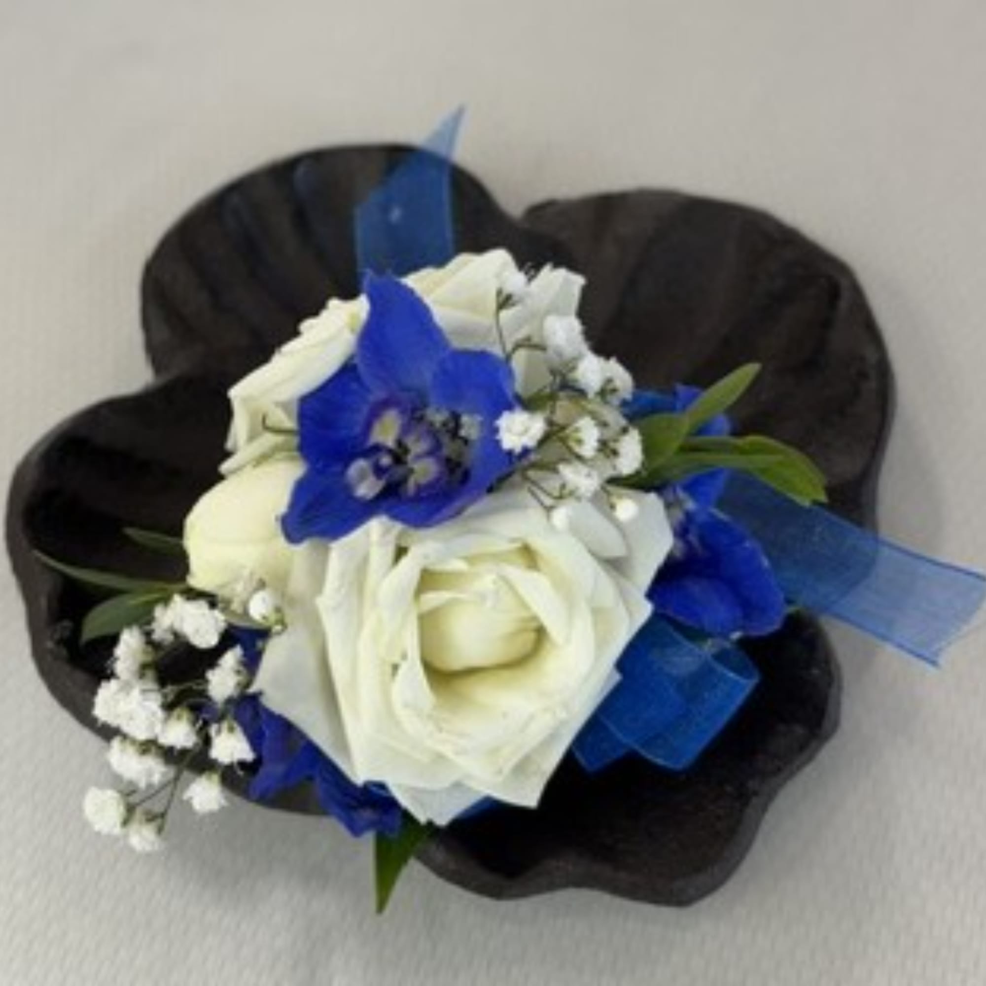 White and blue rose bouquet with baby's breath on a dark wrap