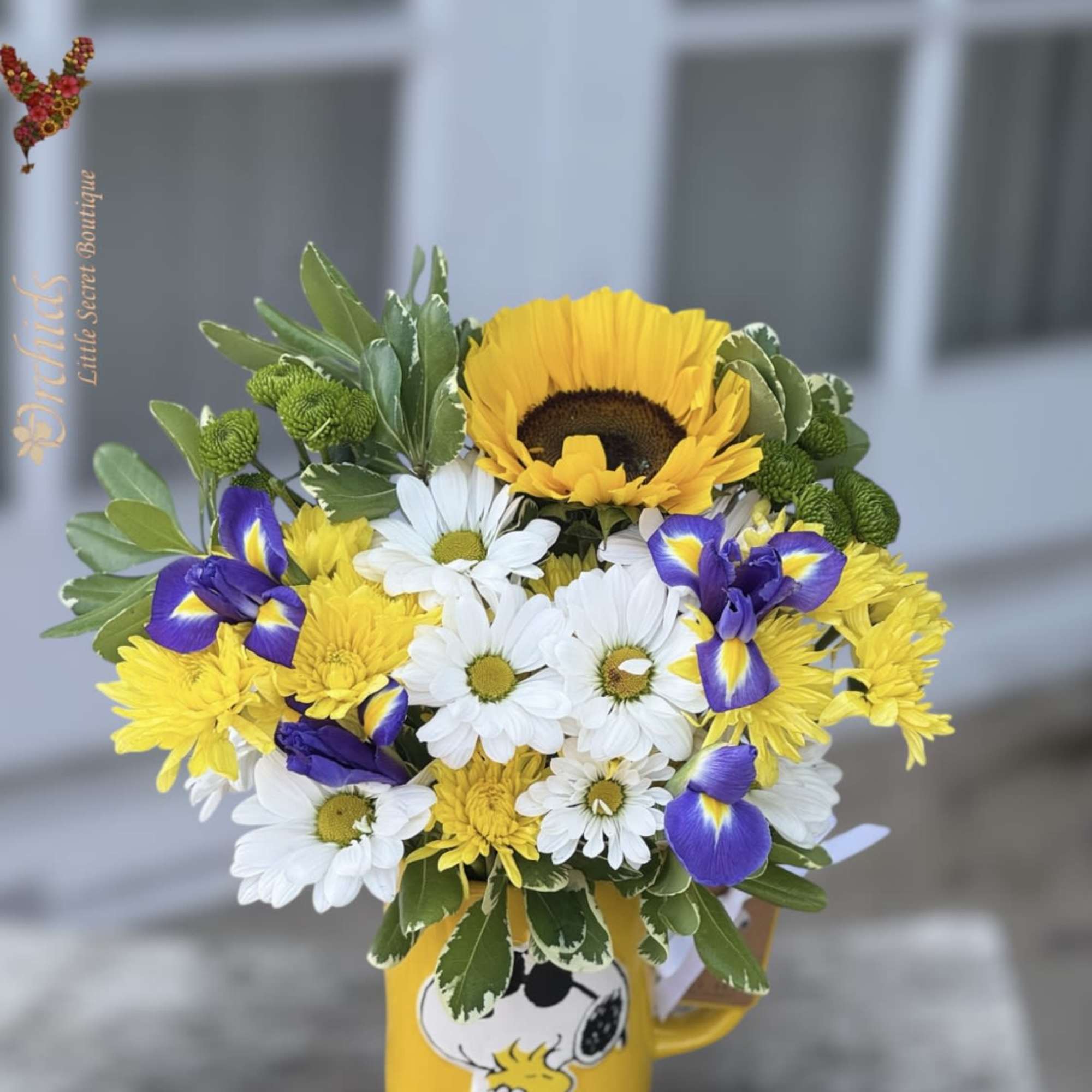 Bouquet of yellow, white, and purple flowers in a Snoopy mug
