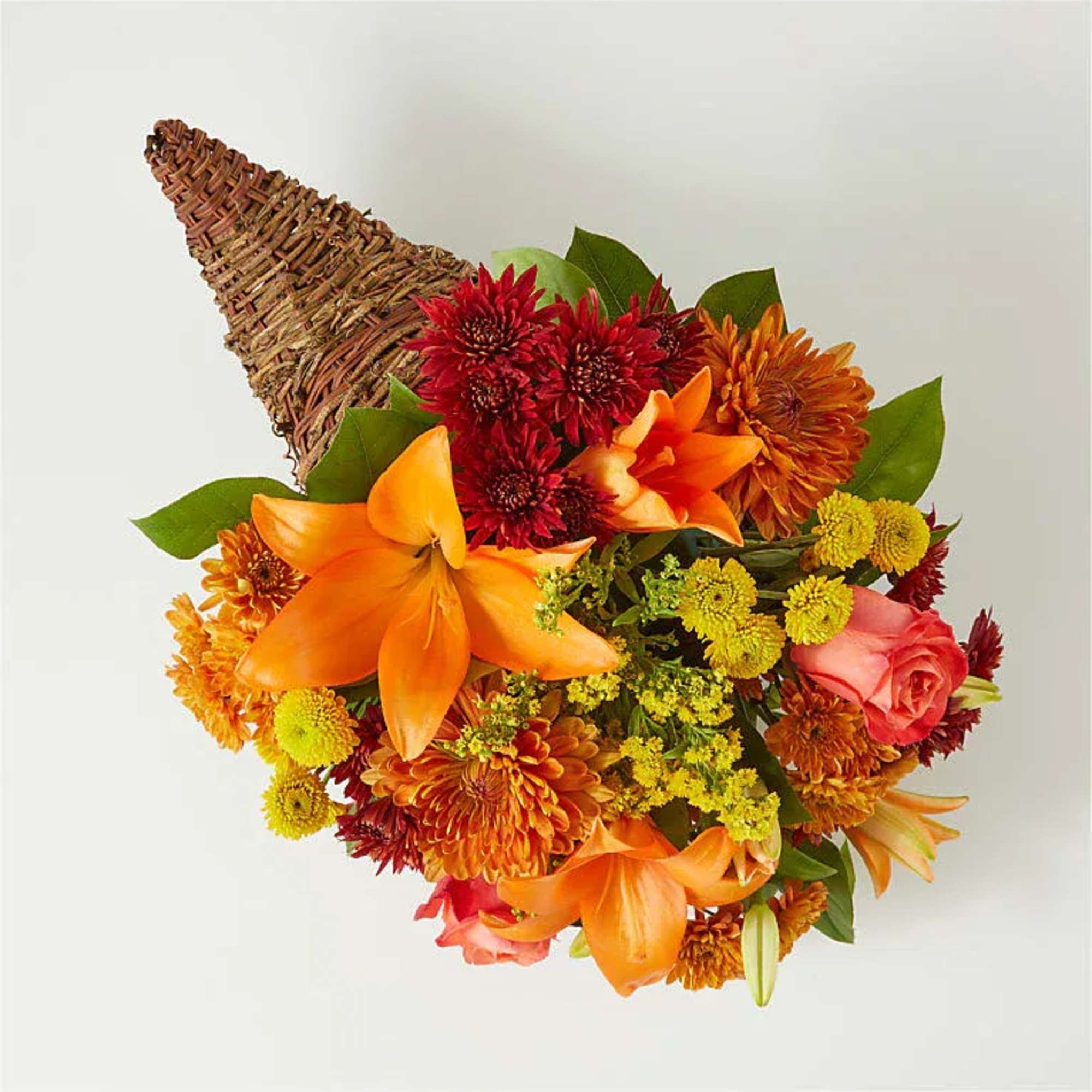 Orange lilies and mixed chrysanthemums in a woven cone holder