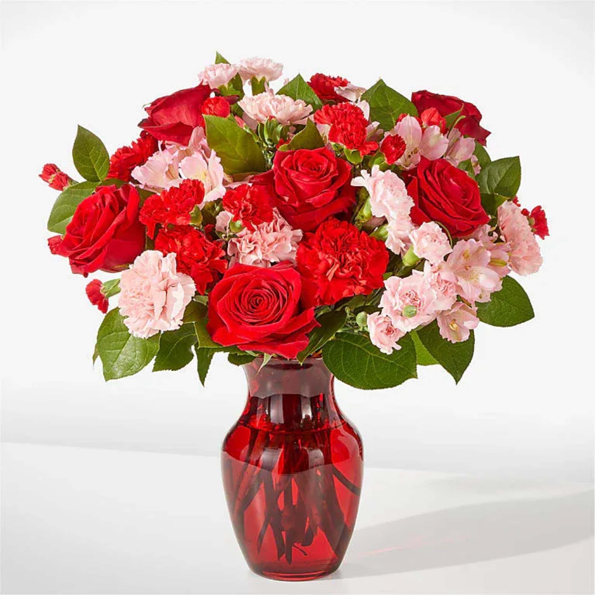 A lush cluster of red roses and pink carnations gathered tight in