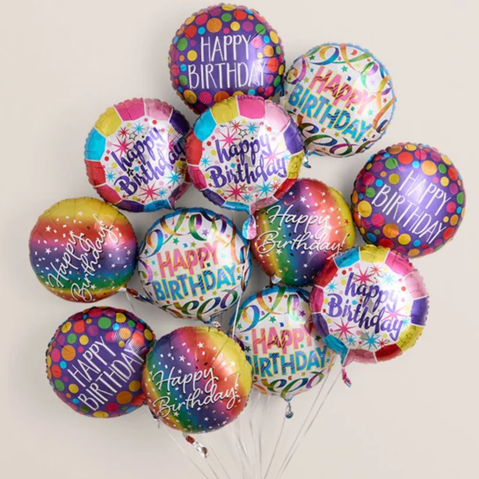 Cluster of colorful "Happy Birthday" balloons against a plain background