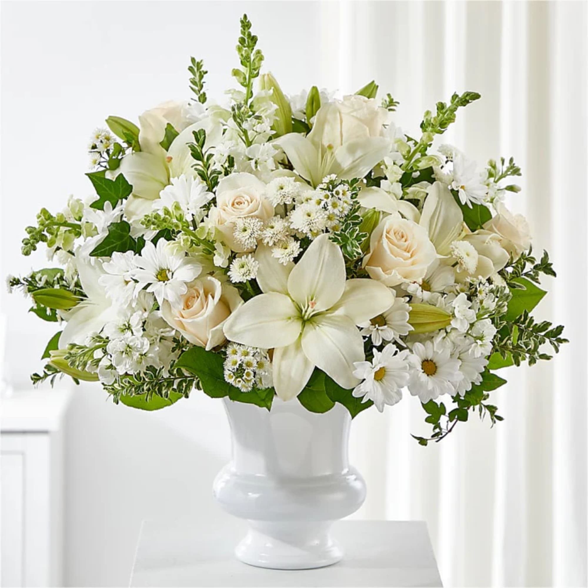 White floral arrangement with roses and lilies in a white vase