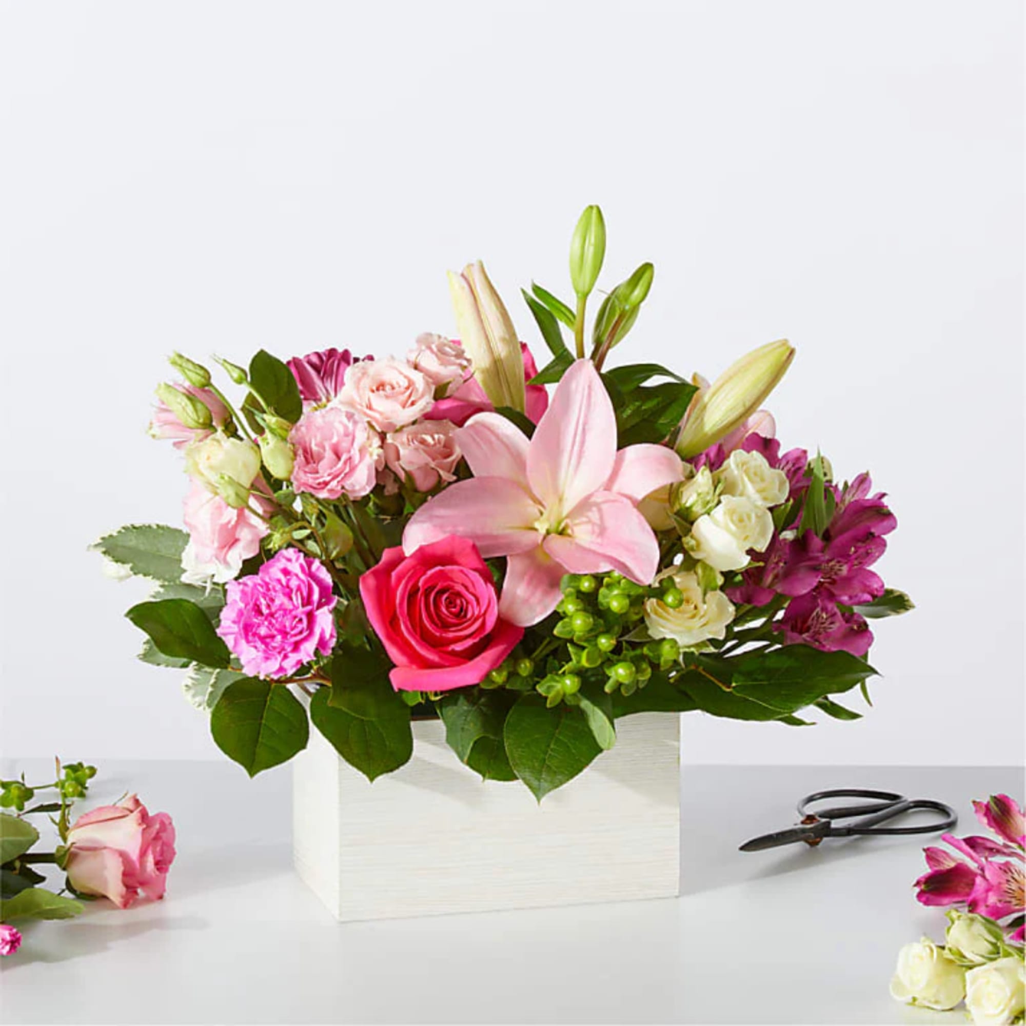 Pink lily and rose arrangement in a white square vase