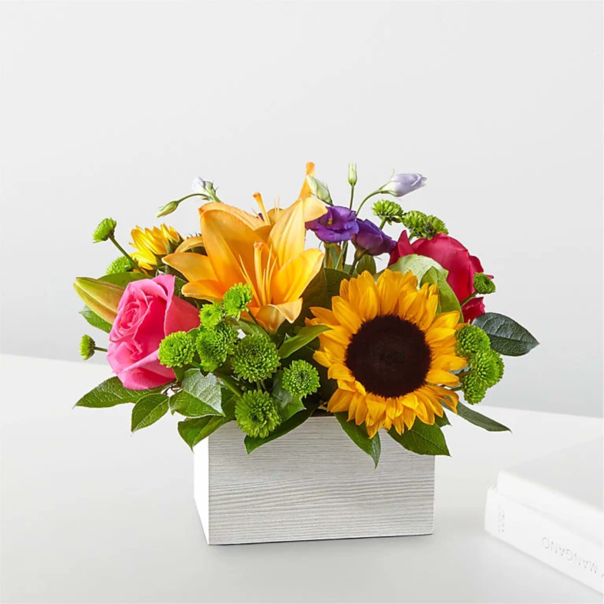 Mixed bouquet with sunflowers, roses, lilies, and purple blooms in a white box