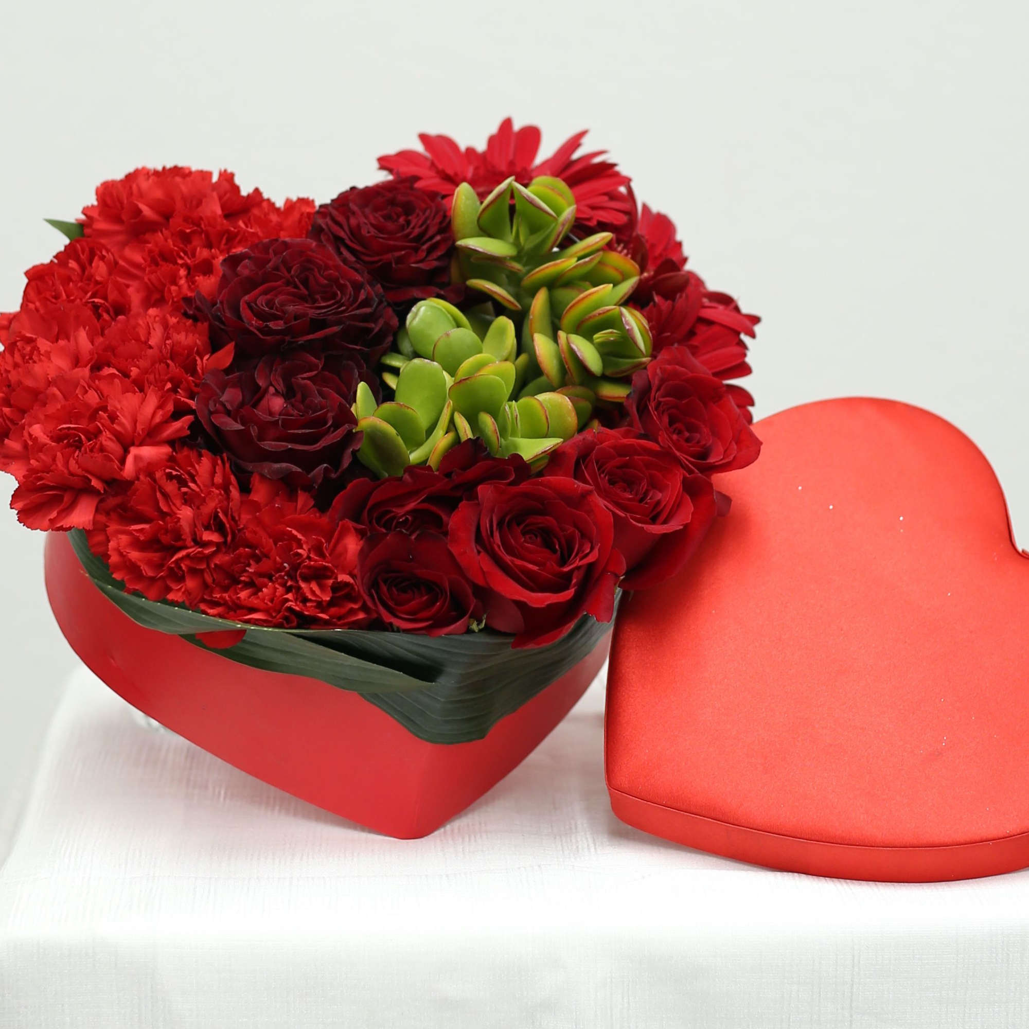 Heart-shaped box of red flowers with a matching heart lid beside it