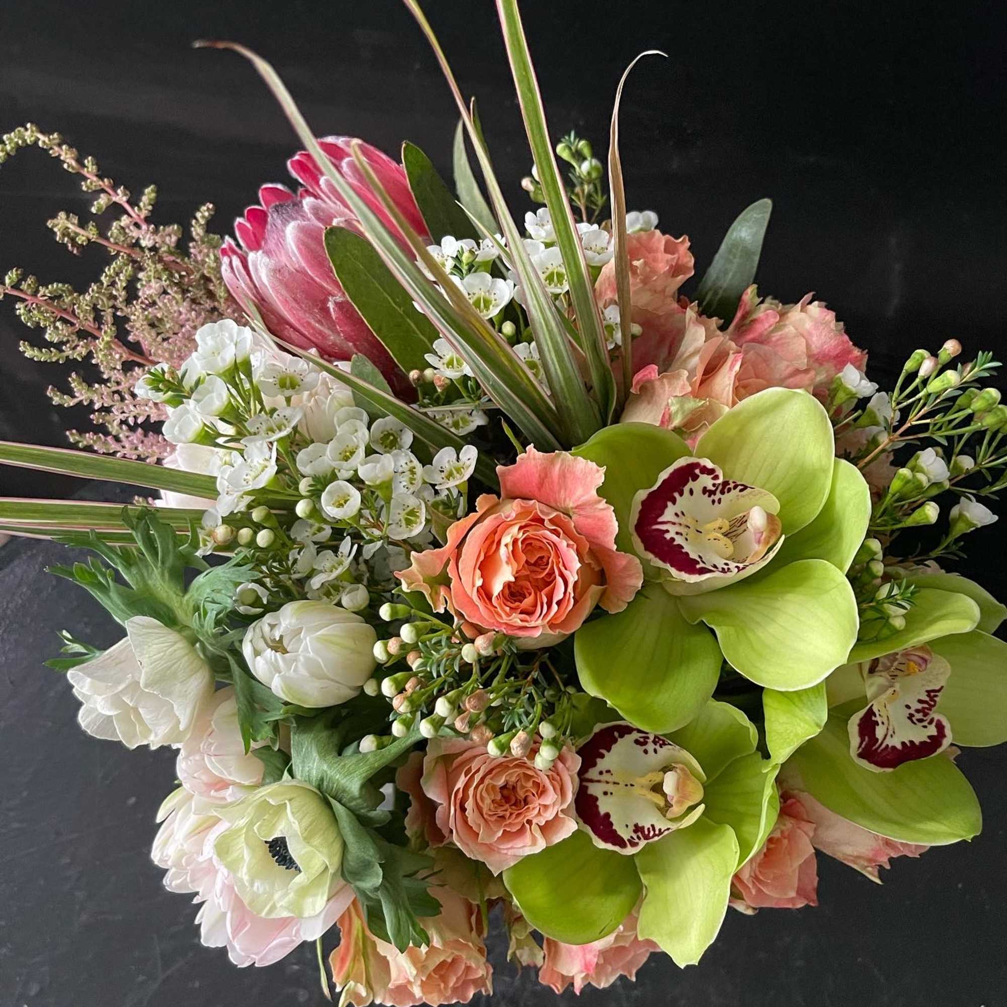 Mixed bouquet with green orchids, peach roses, and white blooms