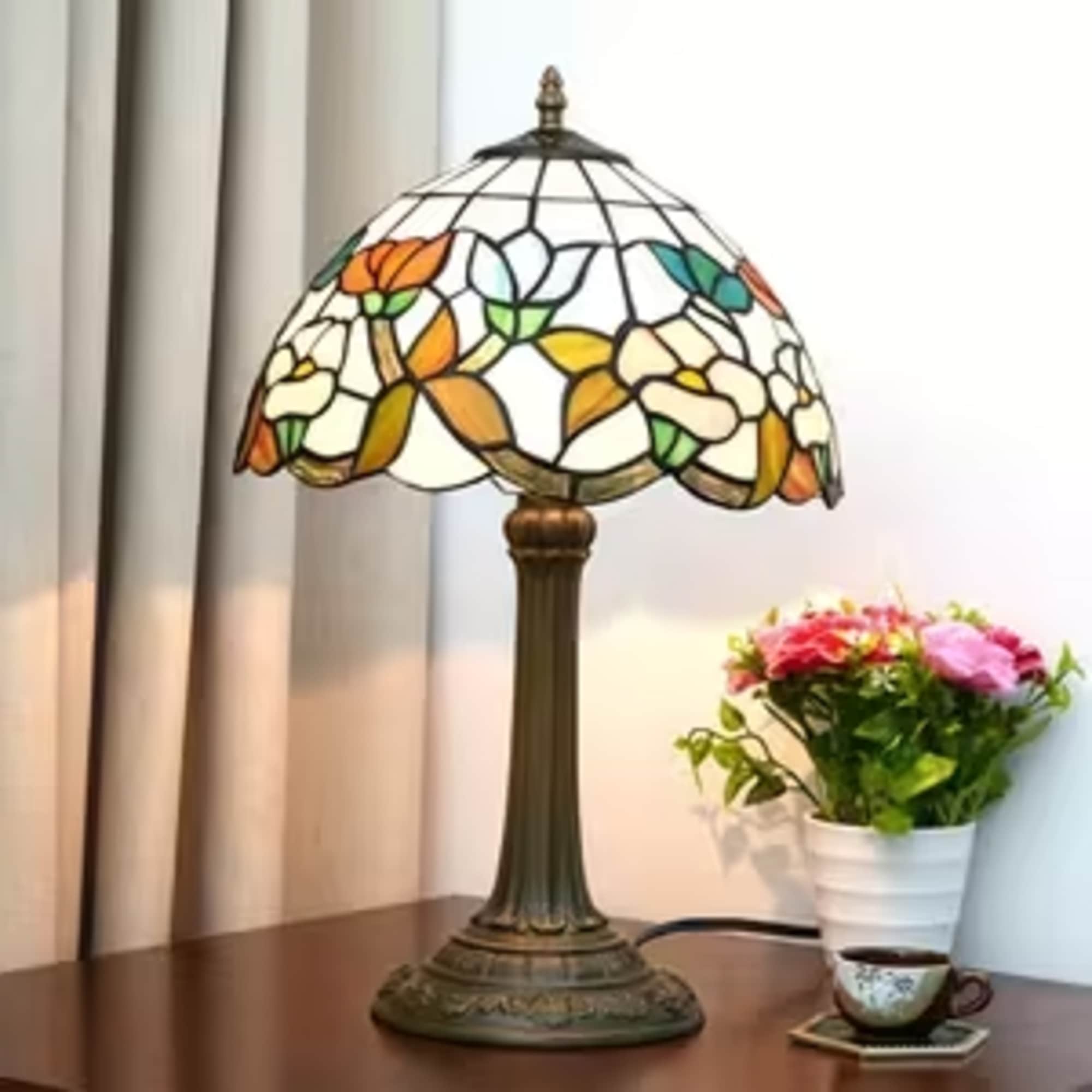 Stained-glass table lamp beside a small potted flower arrangement