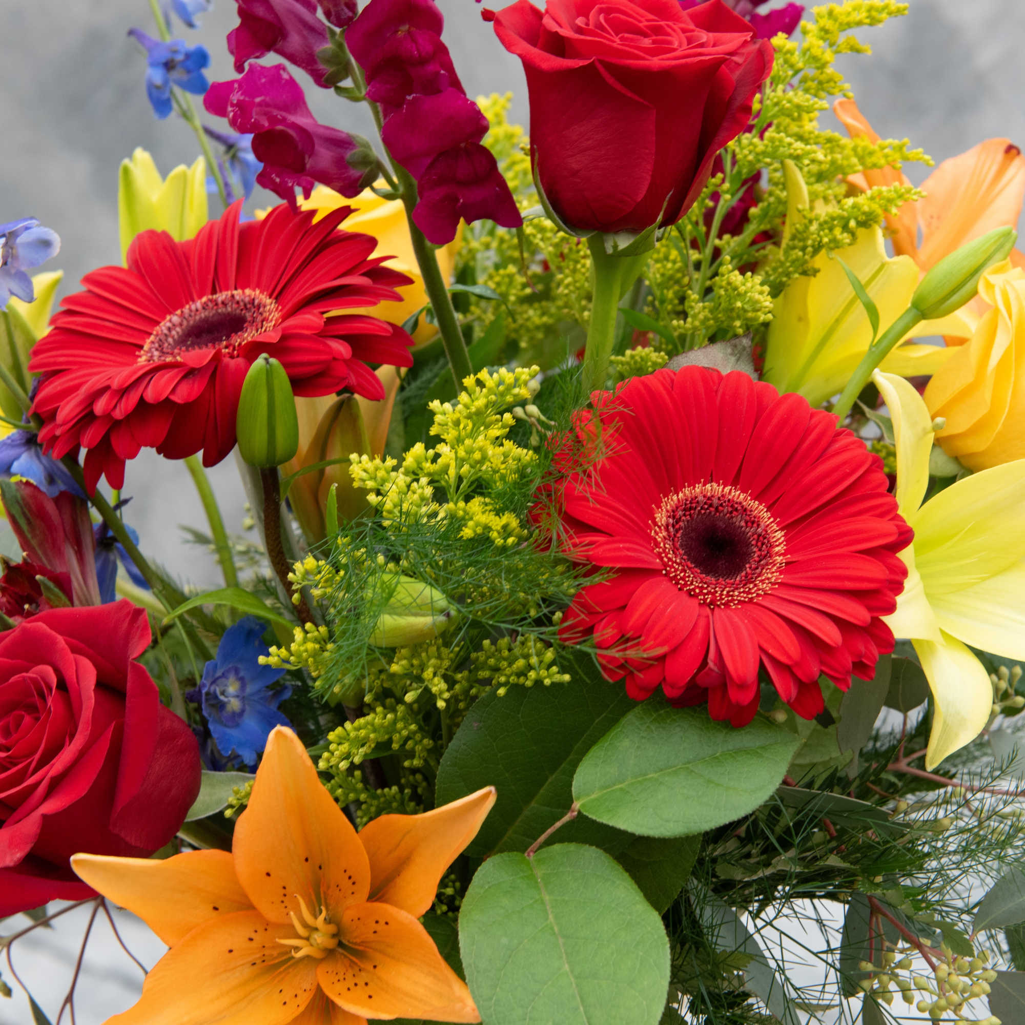 Mixed bouquet with red roses, red gerbera daisies, and orange lilies
