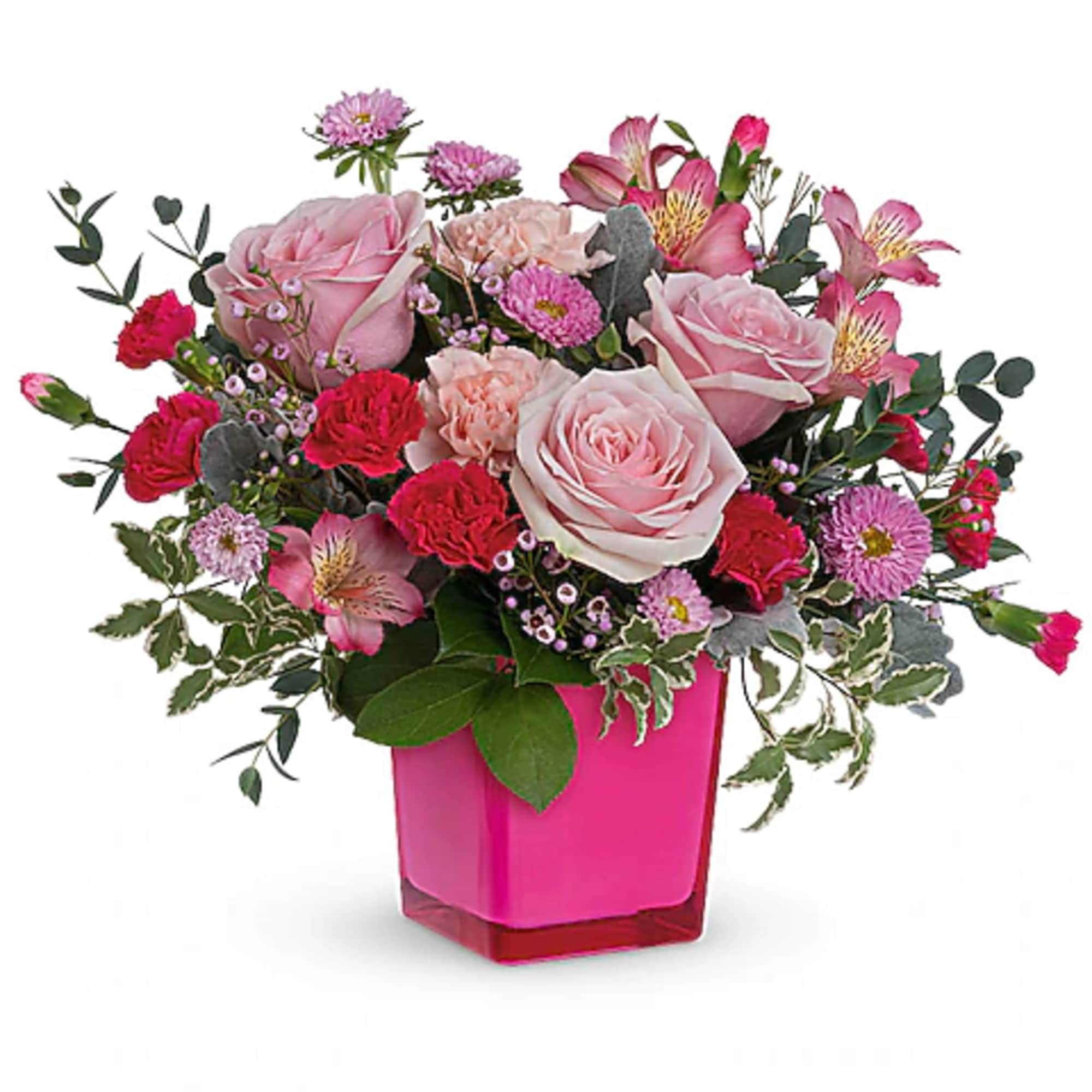 Pink roses and mixed blooms arranged in a bright pink vase