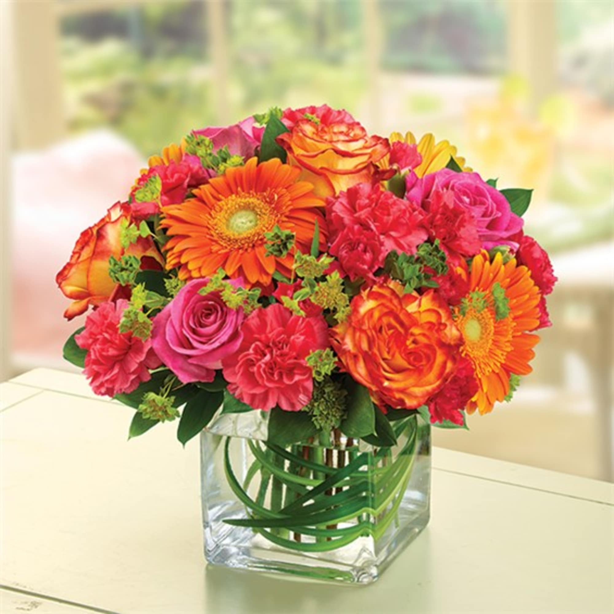 Bright mixed bouquet in a clear square glass vase