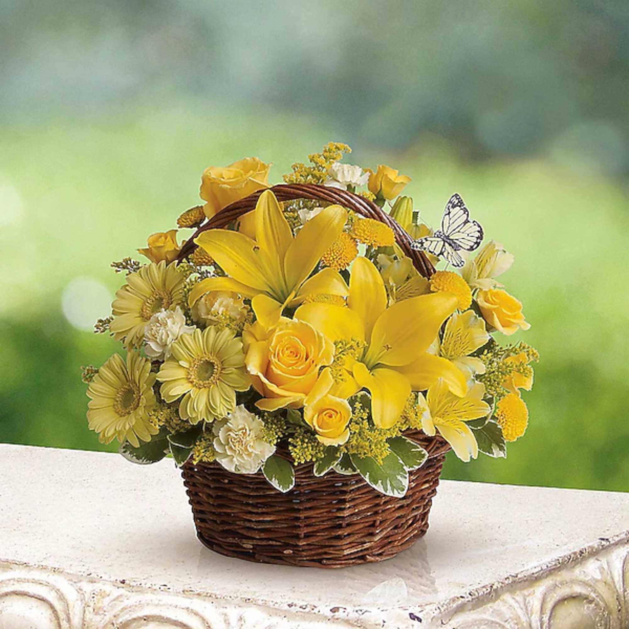 Yellow floral basket arrangement with lilies and roses in a wicker basket