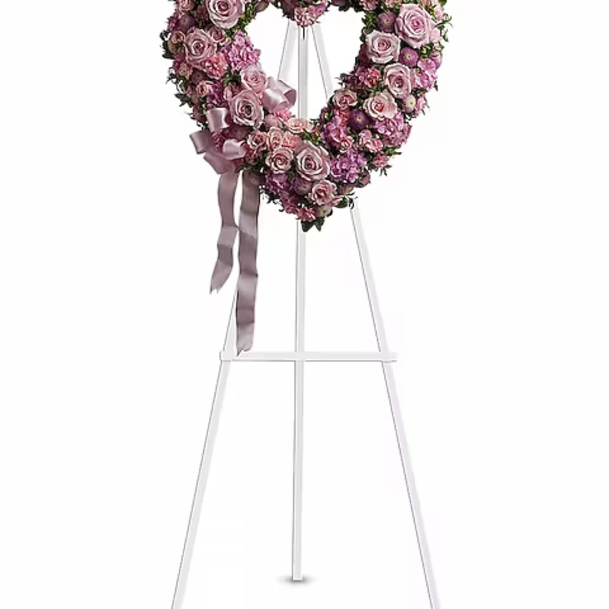 Heart-shaped pink rose wreath on a white easel with ribbon