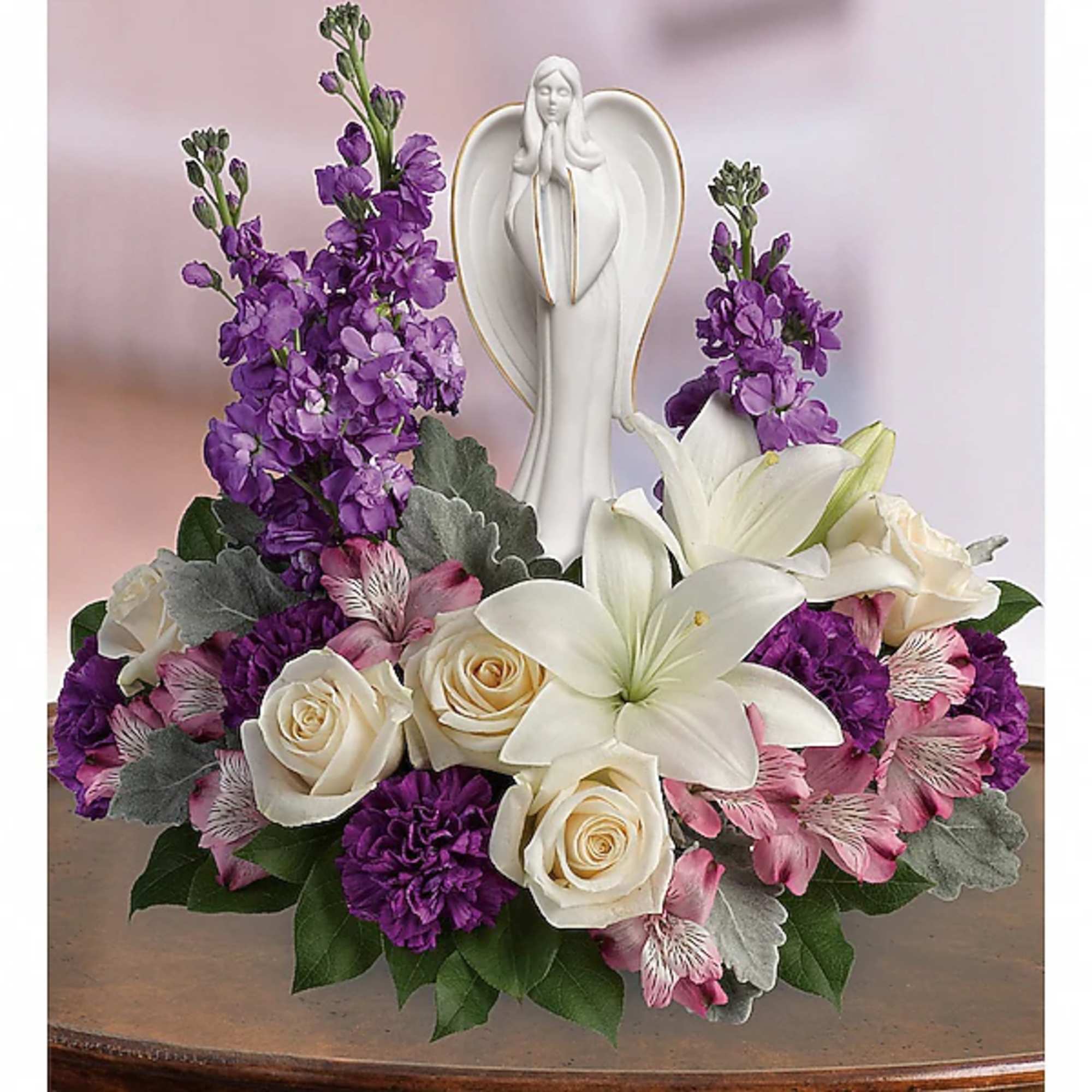 Purple and white floral arrangement with a white angel figurine