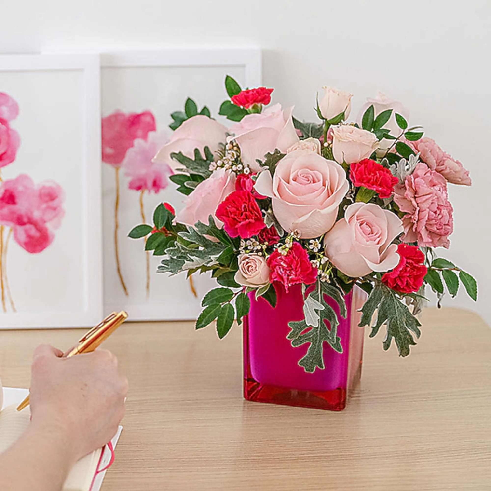 Pink roses and carnations arranged in a red glass vase
