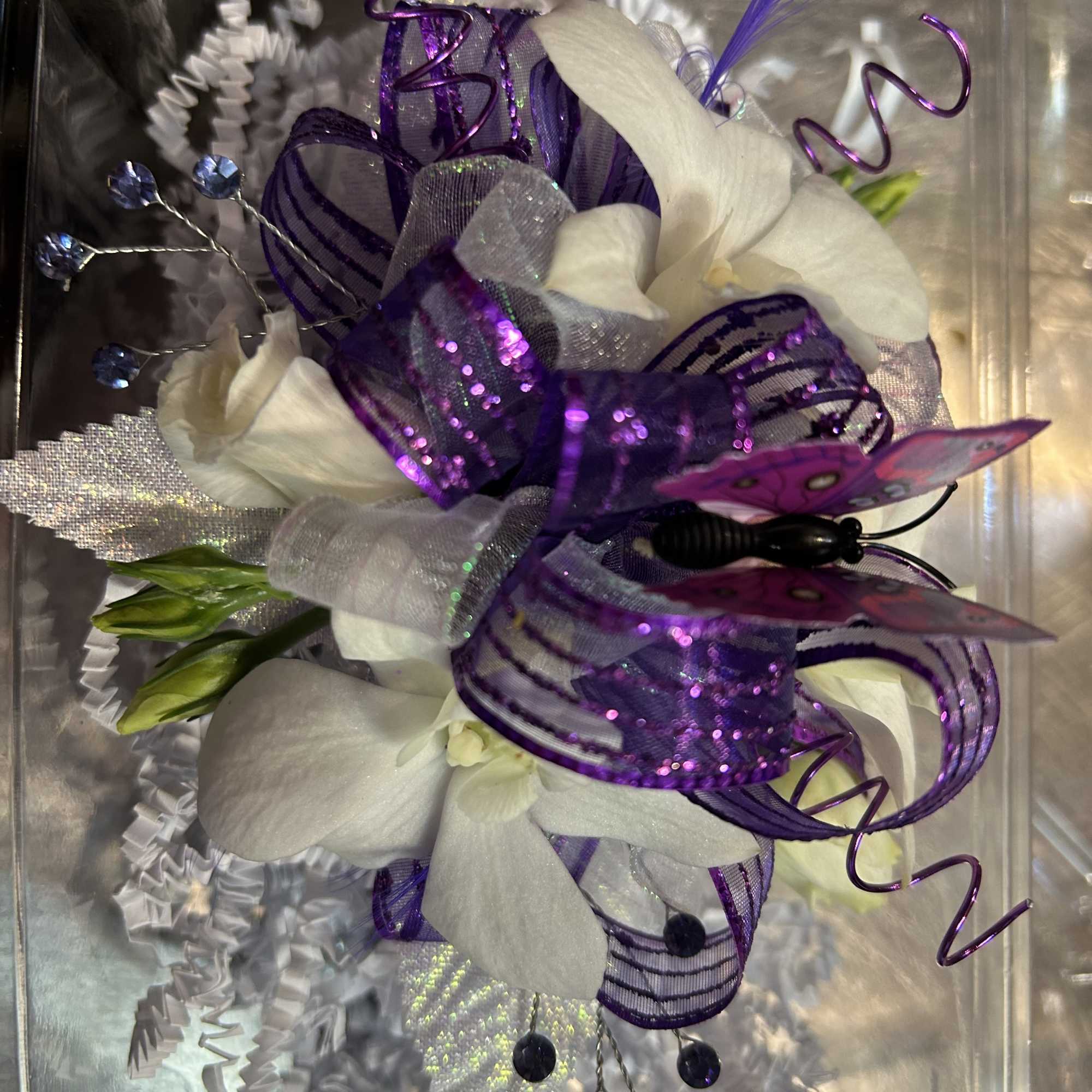 White orchid corsage with purple ribbon and butterfly decoration