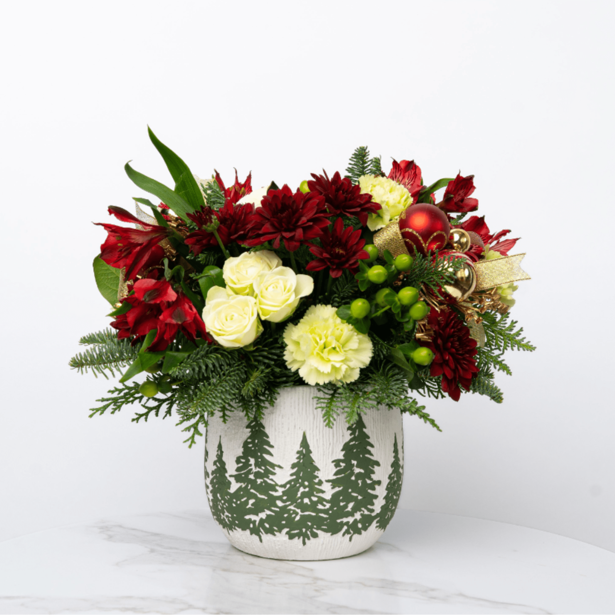 Holiday floral arrangement in a white pot with red and cream flowers