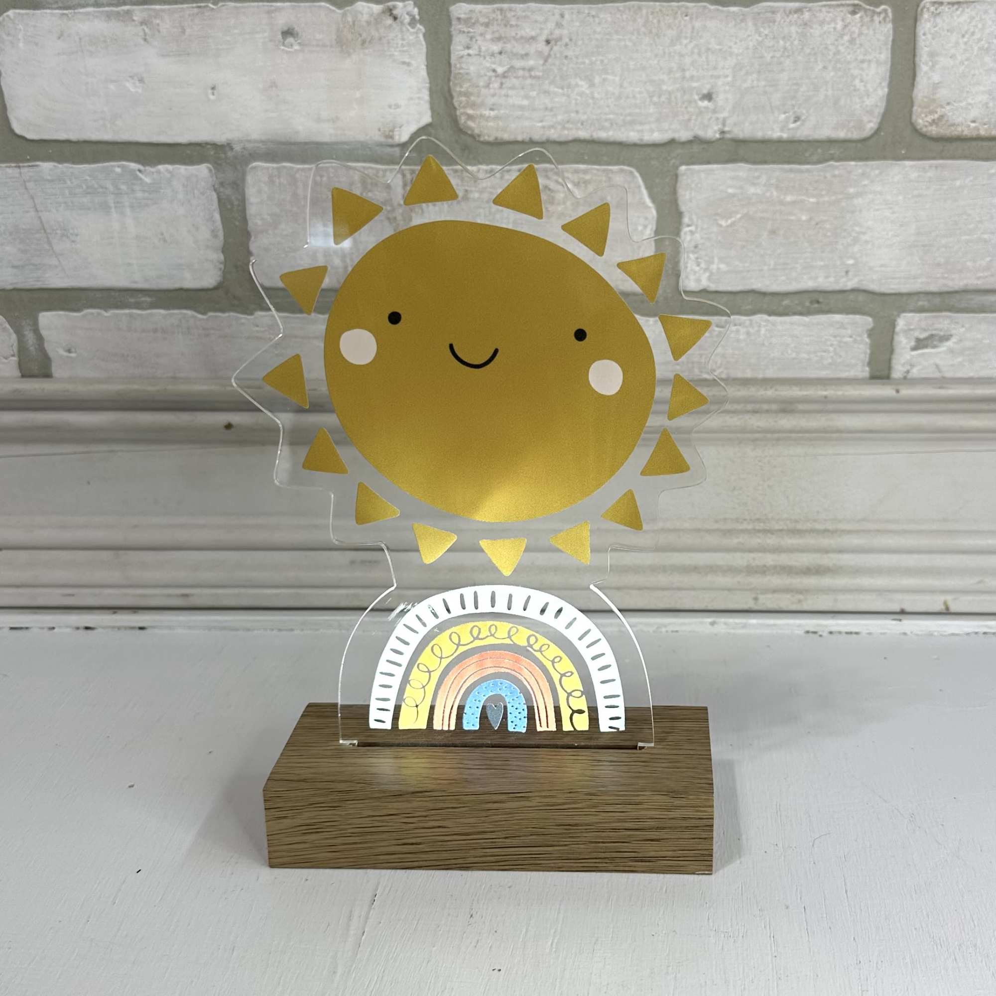A smiling sun and rainbow acrylic tabletop decoration on a wooden base