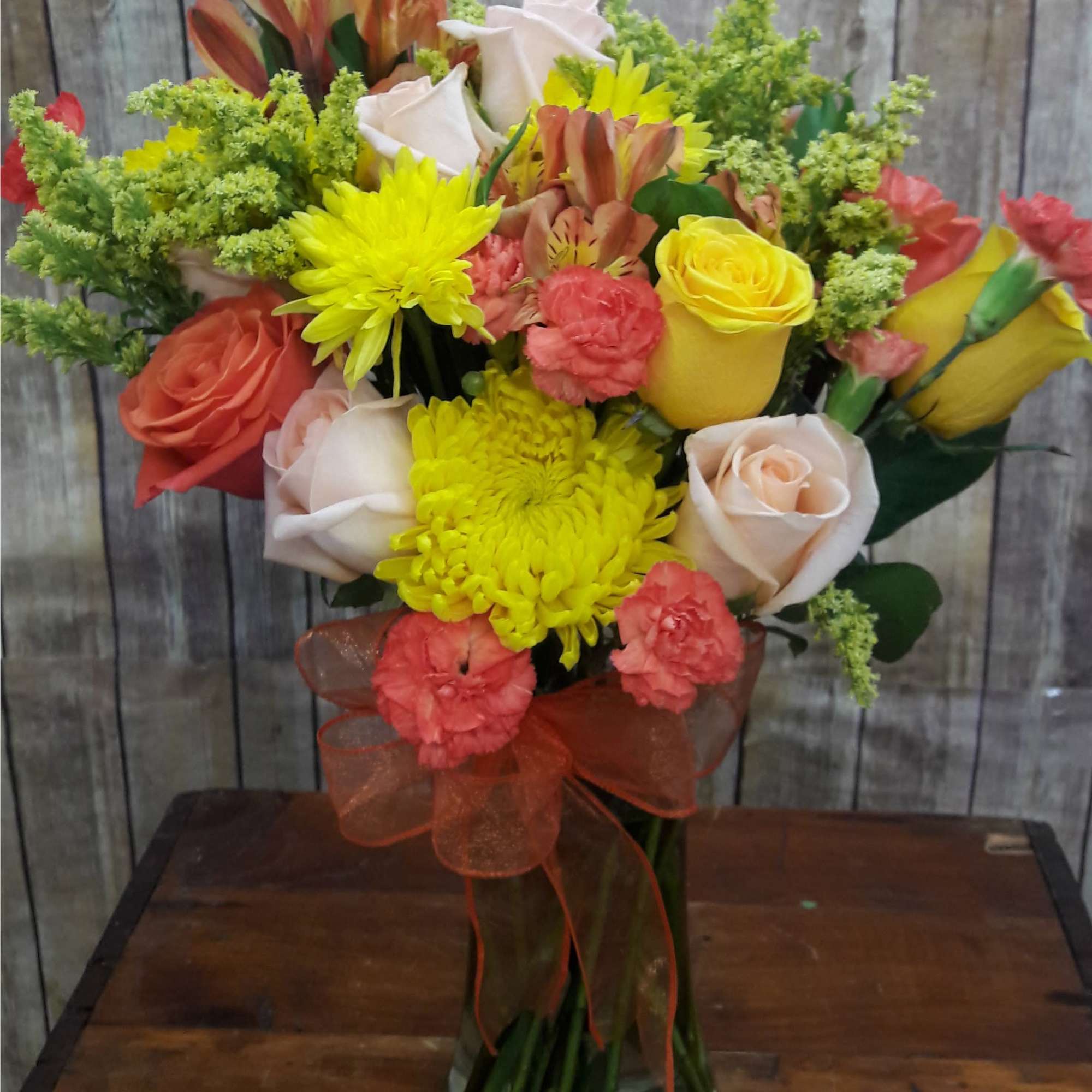 Mixed bouquet of roses, chrysanthemums, and alstroemeria in a glass vase