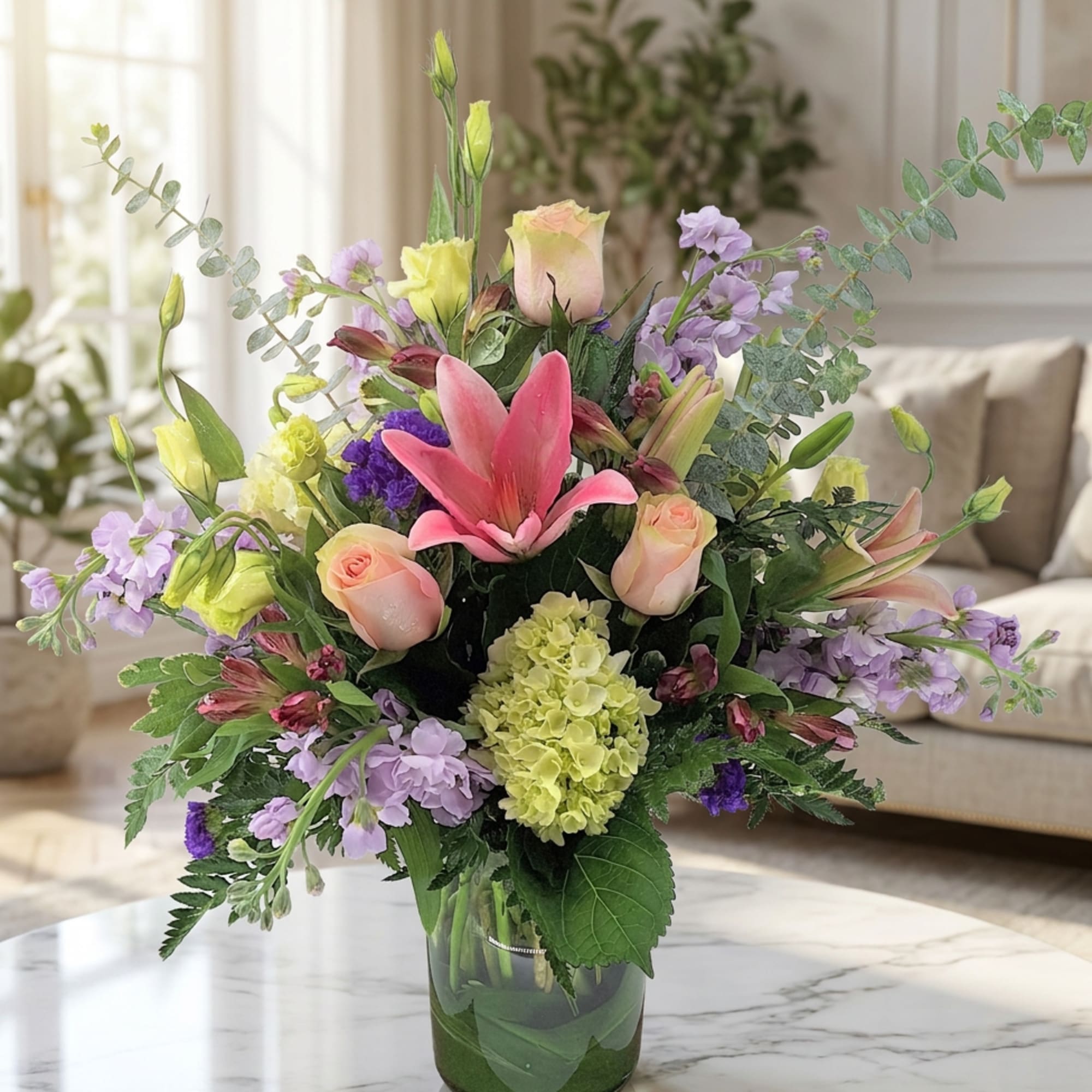 Mixed bouquet with pink lilies, roses, and lavender flowers in a glass vase